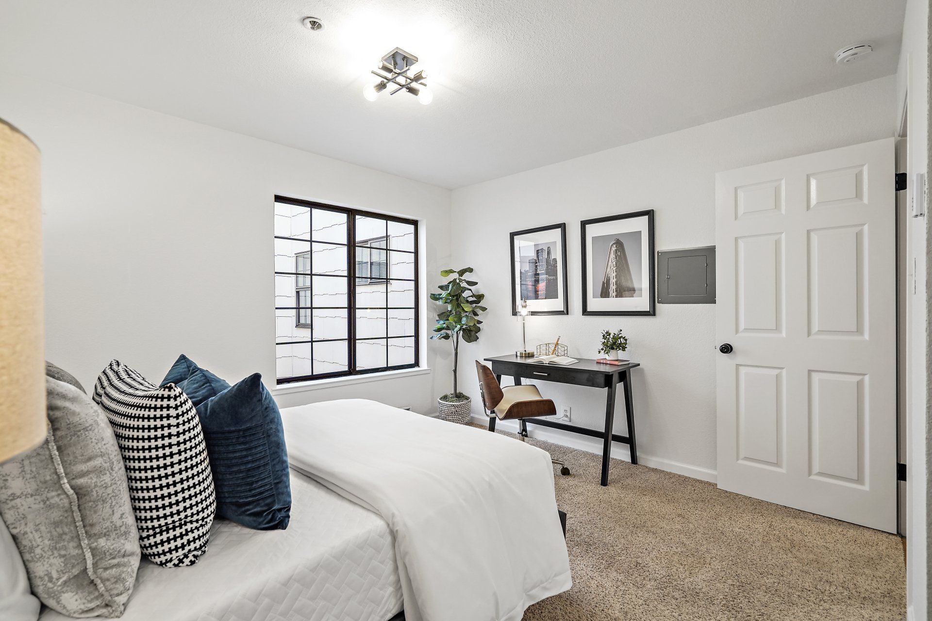 A bedroom with a bed , a desk and a window.