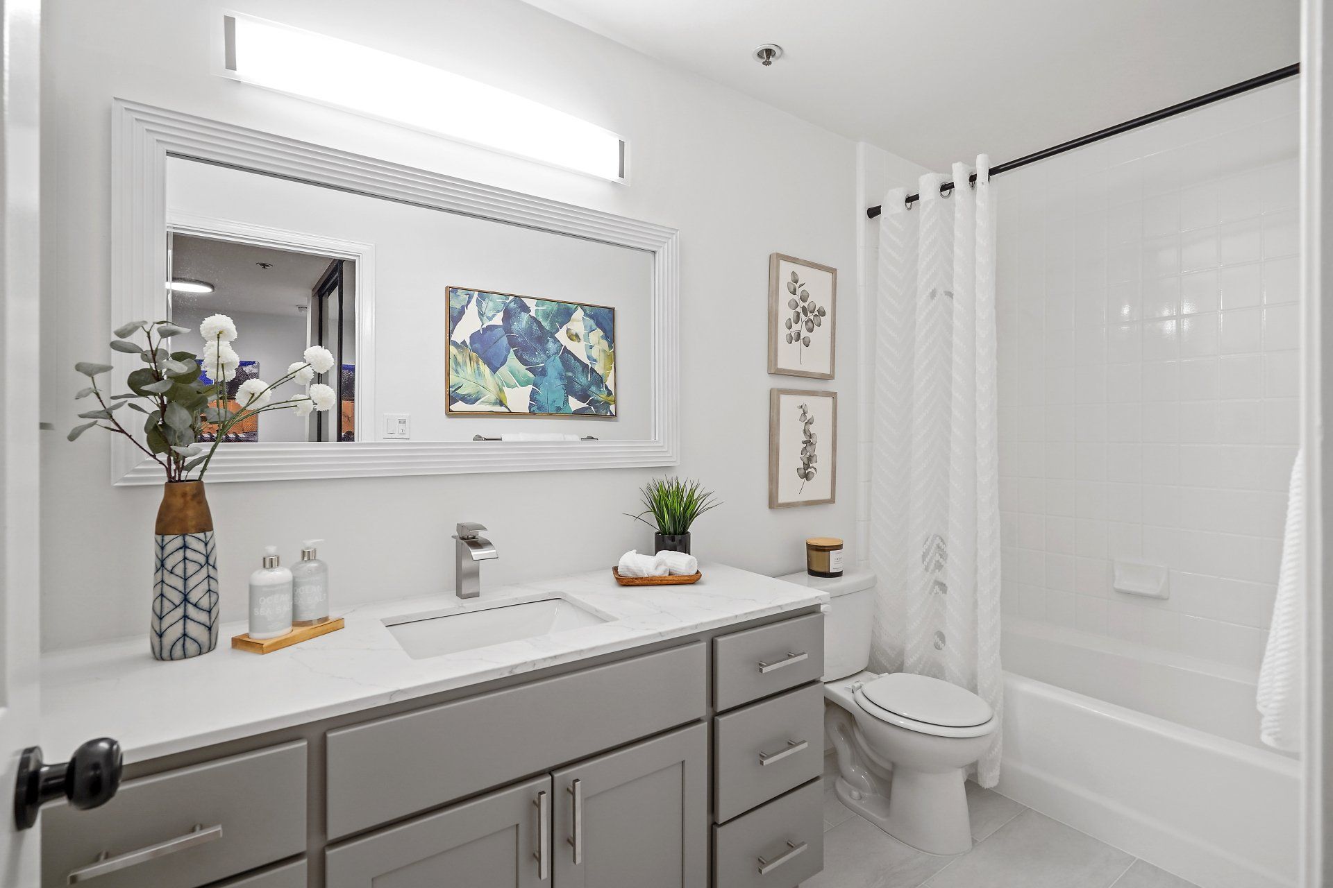 A bathroom with a sink , toilet , tub and mirror.