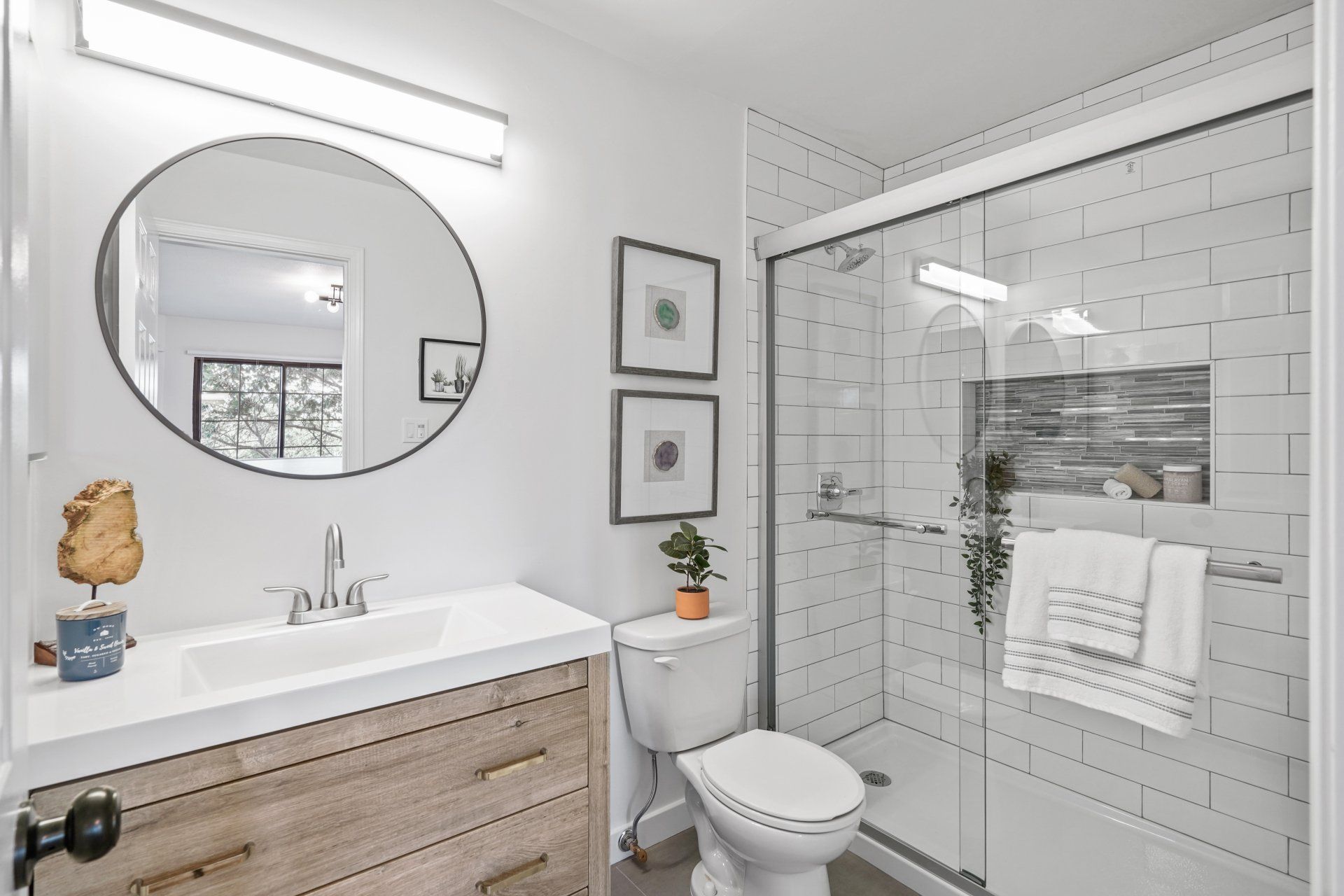 A bathroom with a toilet , sink , mirror and shower stall.