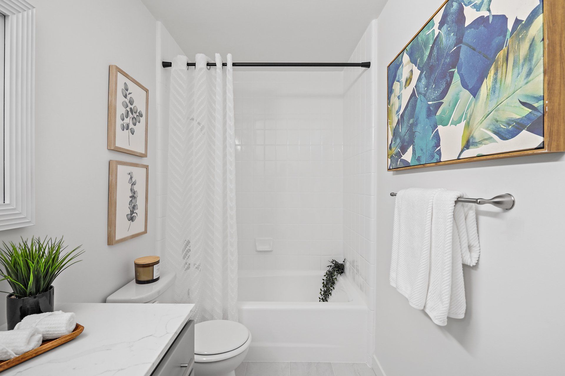 A bathroom with a toilet , bathtub , and painting on the wall.