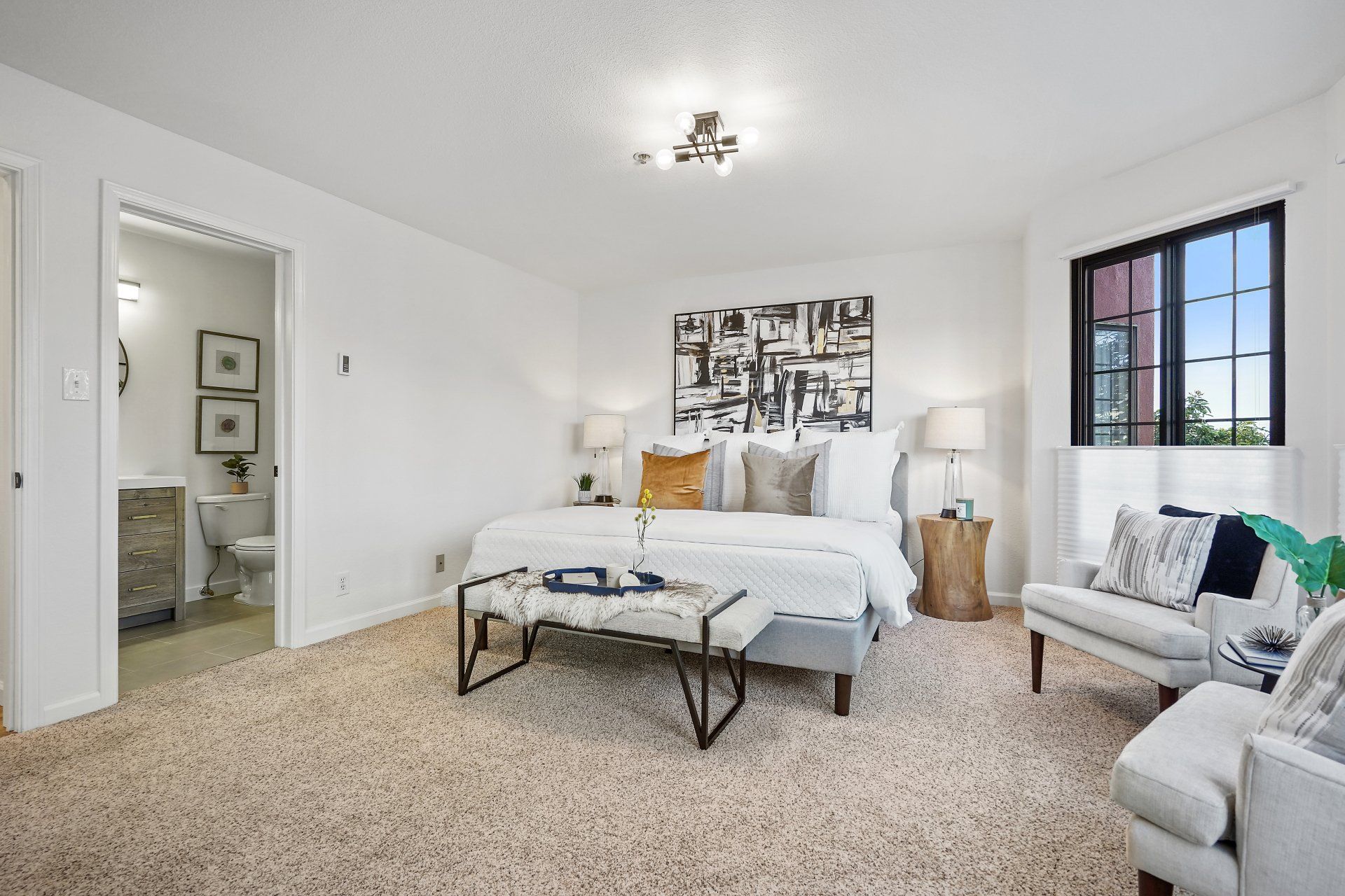 A bedroom with a bed , chairs , and a window.