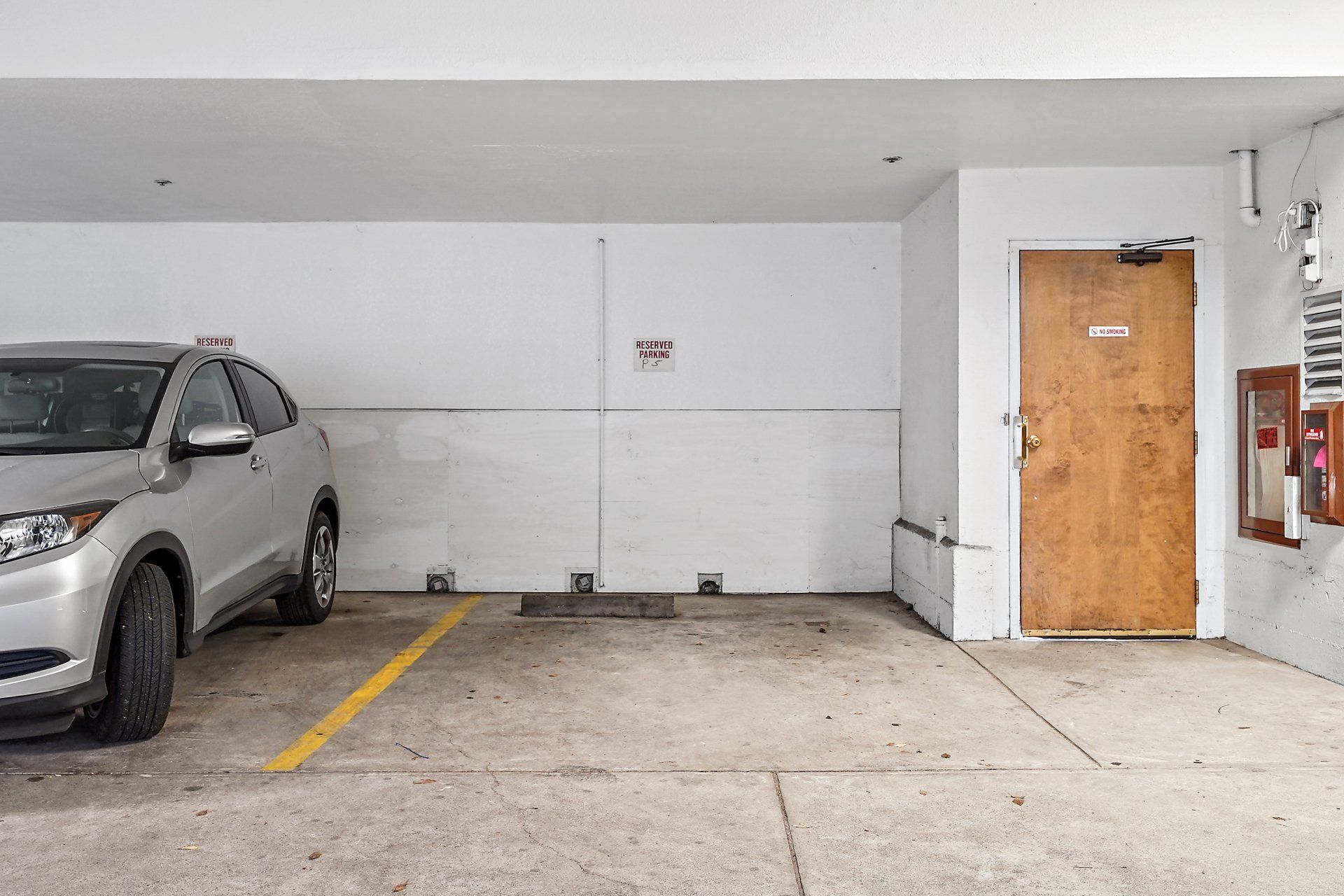 A car is parked in a parking garage next to a door.