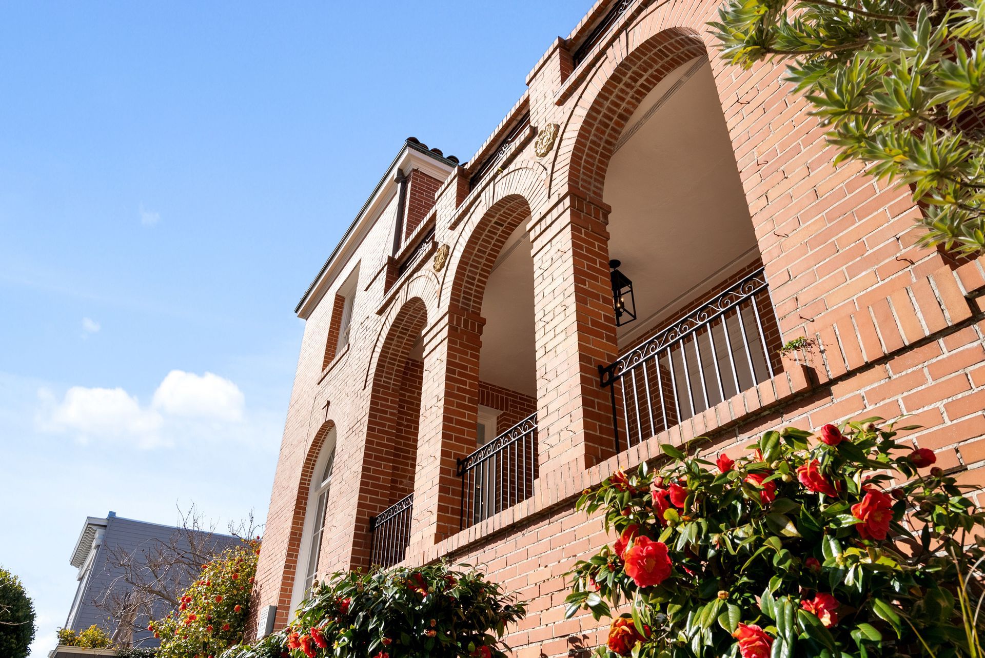 A large brick building with arches and flowers in front of it