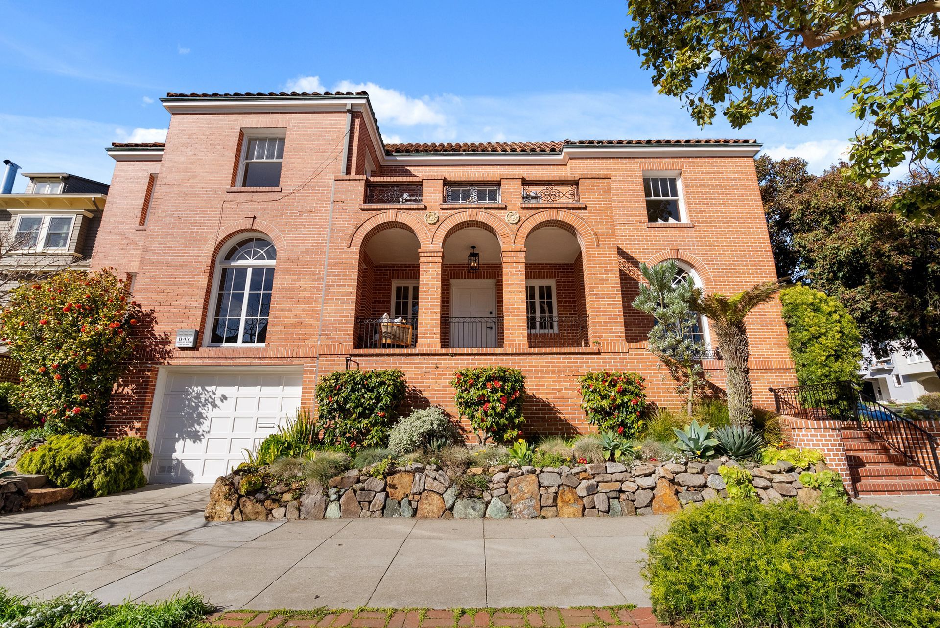 A large brick house with arched windows and a white garage