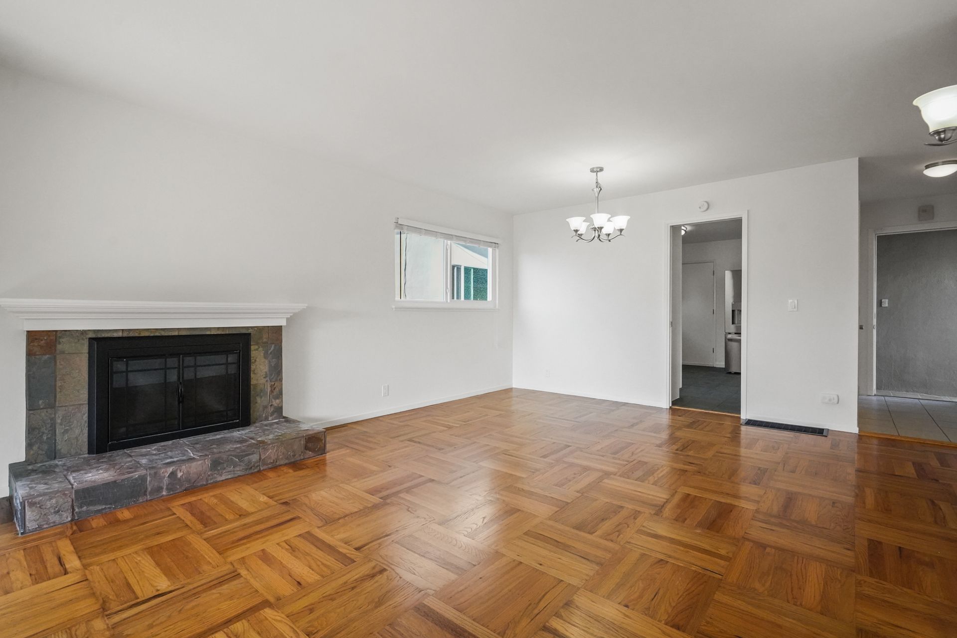 An empty living room with hardwood floors and a fireplace.