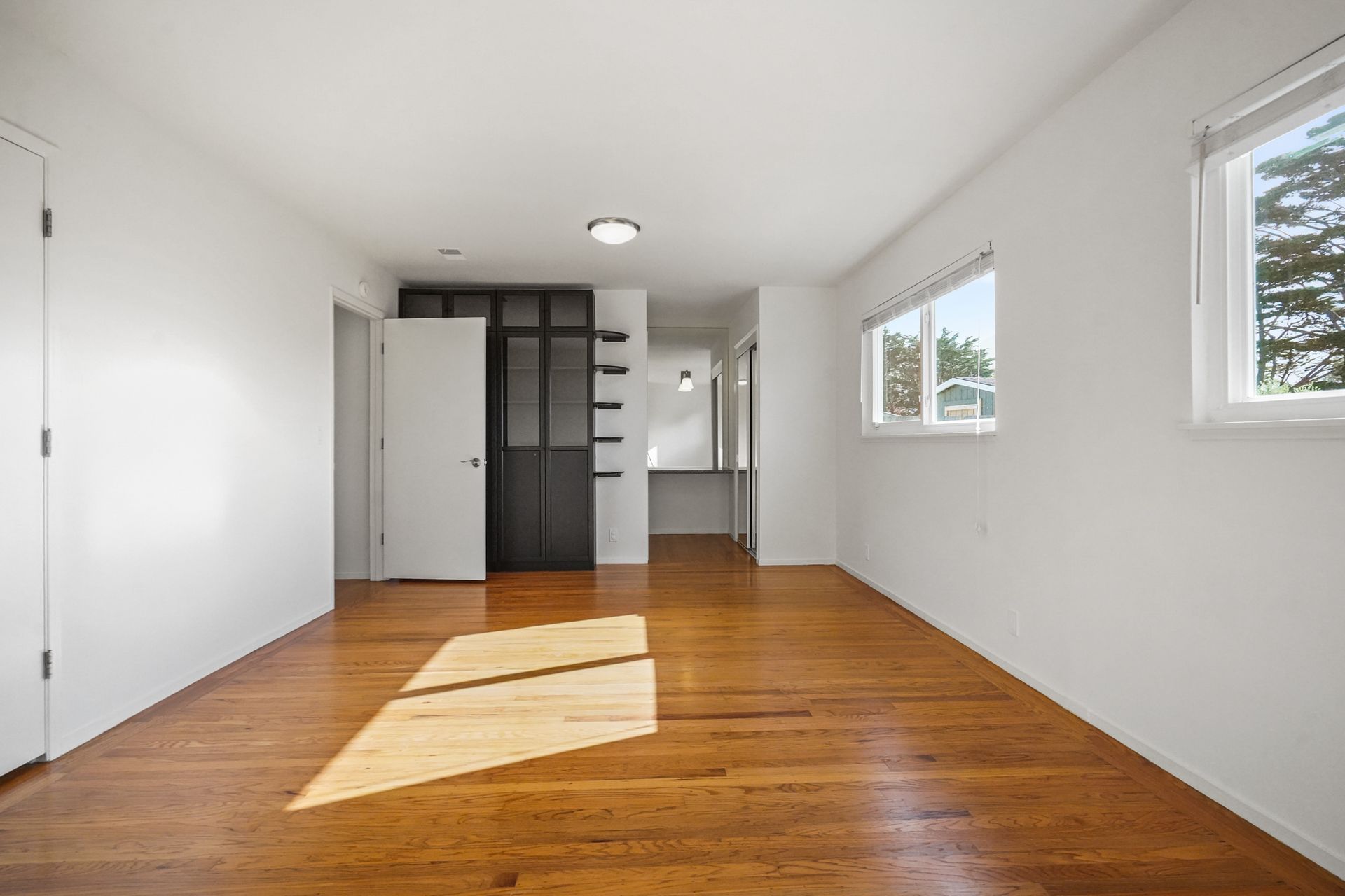 An empty room with hardwood floors and white walls