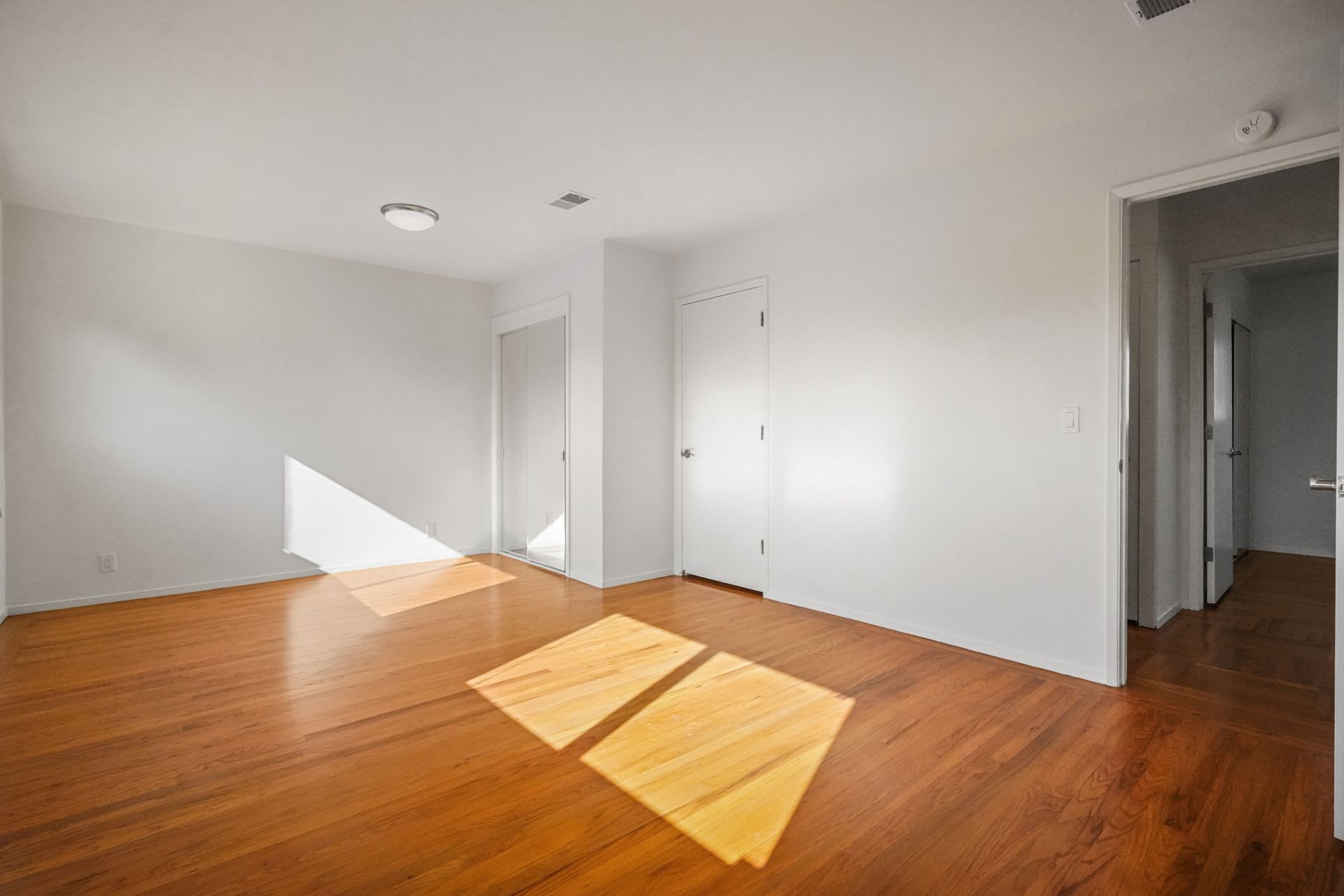 An empty room with hardwood floors and white walls.