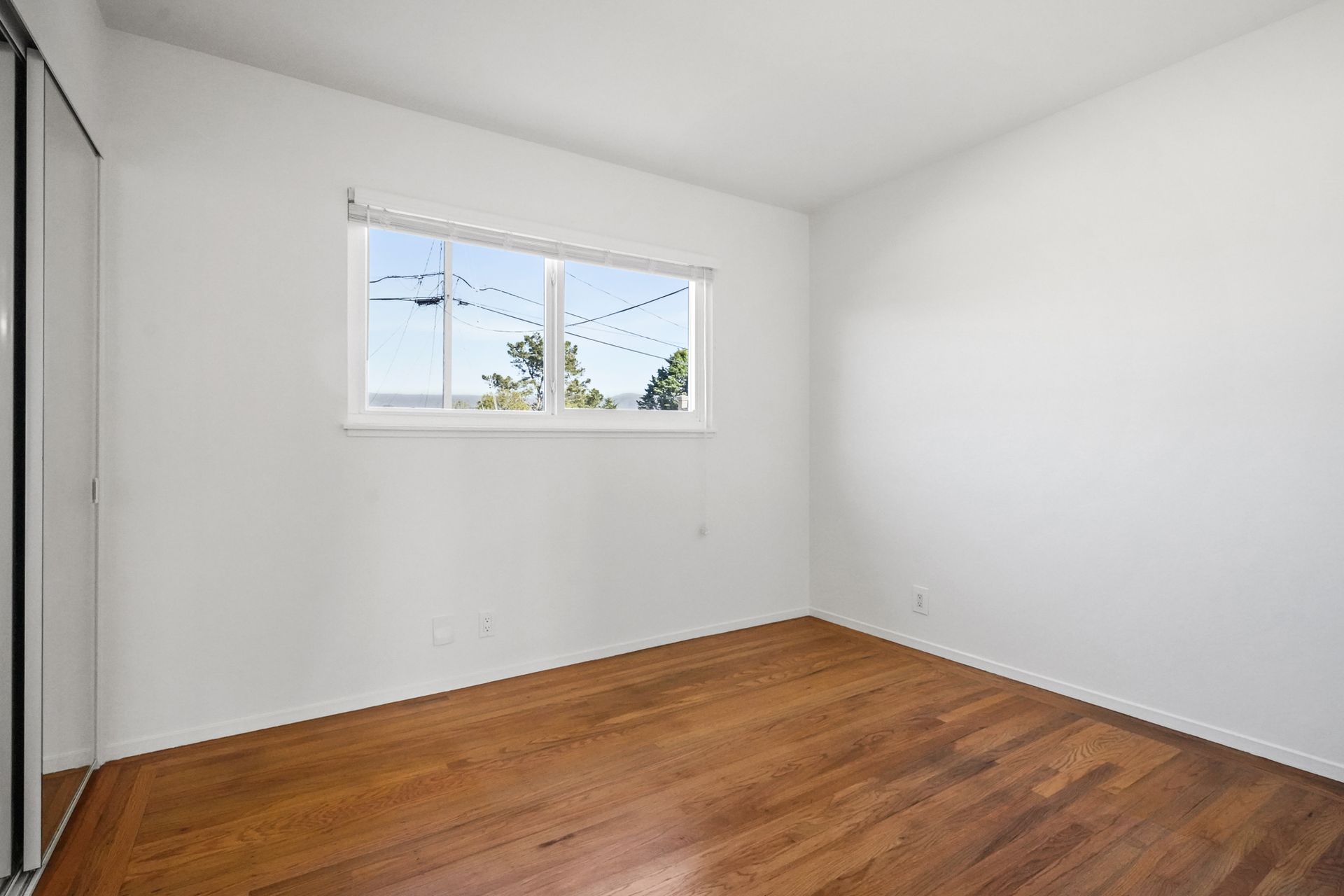 An empty room with hardwood floors and a window