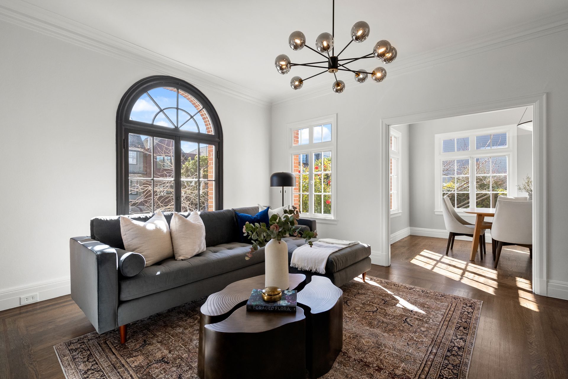 A living room with a couch , coffee table , and chandelier.