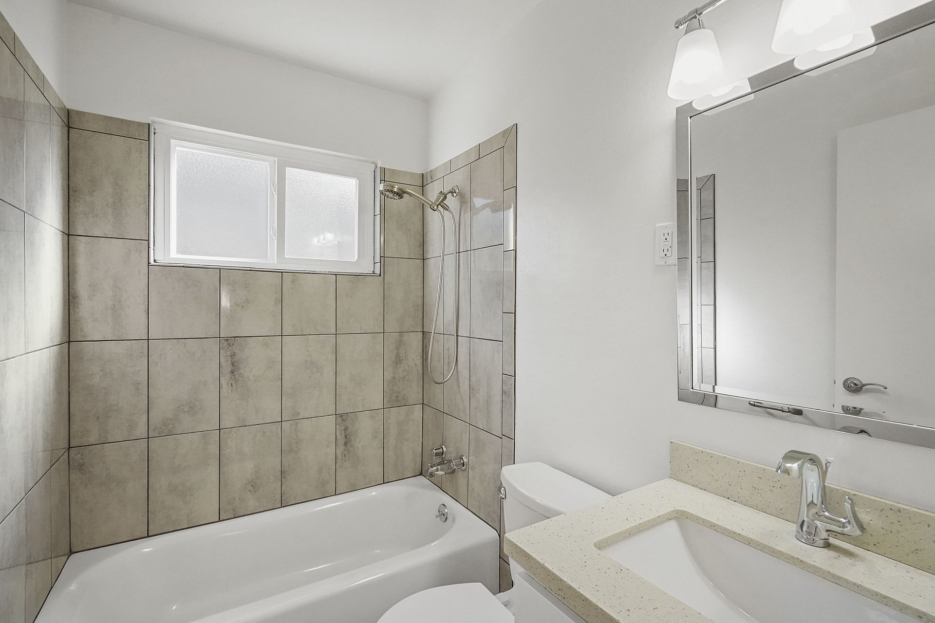 A bathroom with a tub , toilet , sink and mirror.