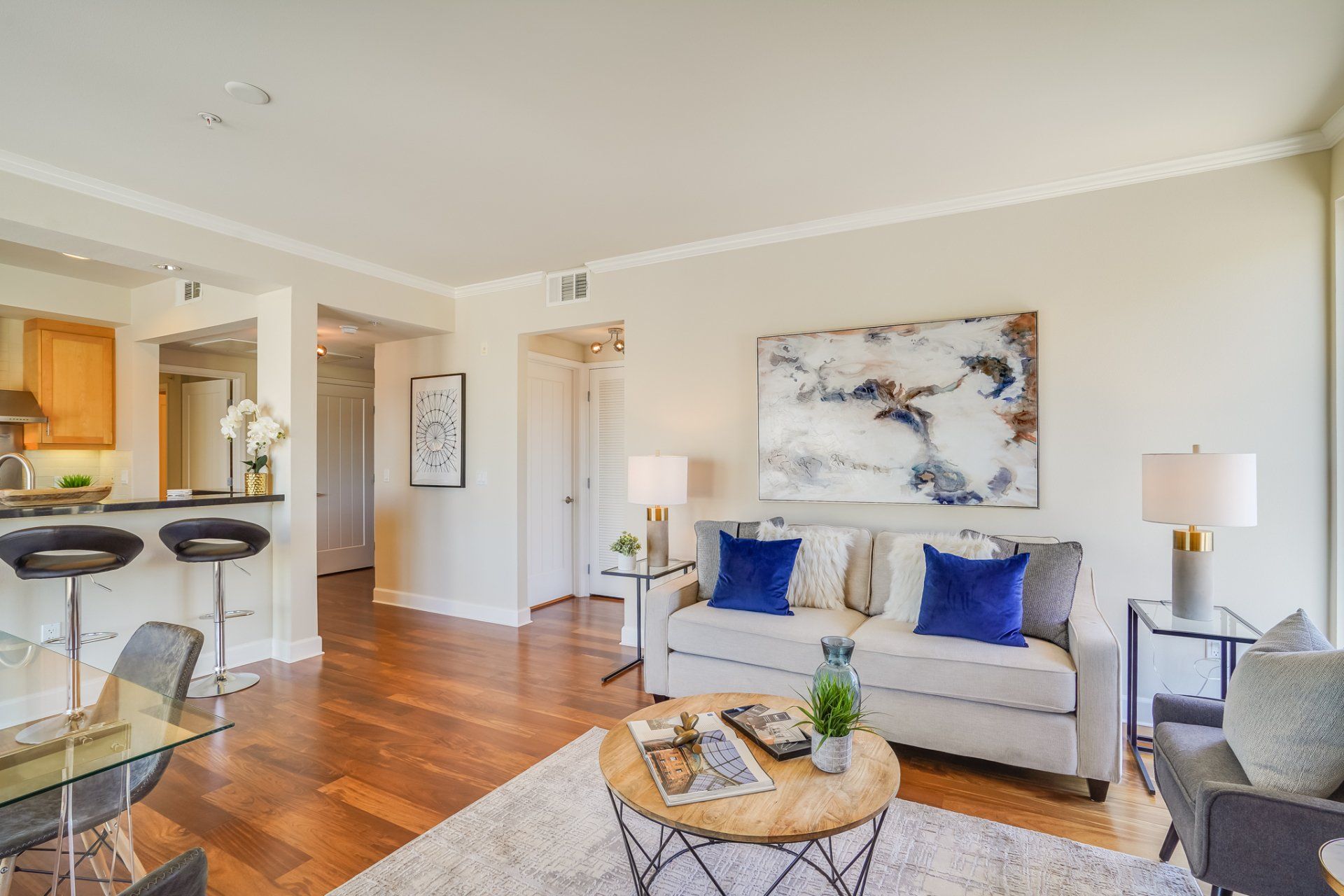 A living room with a couch , table , chairs and a painting on the wall.