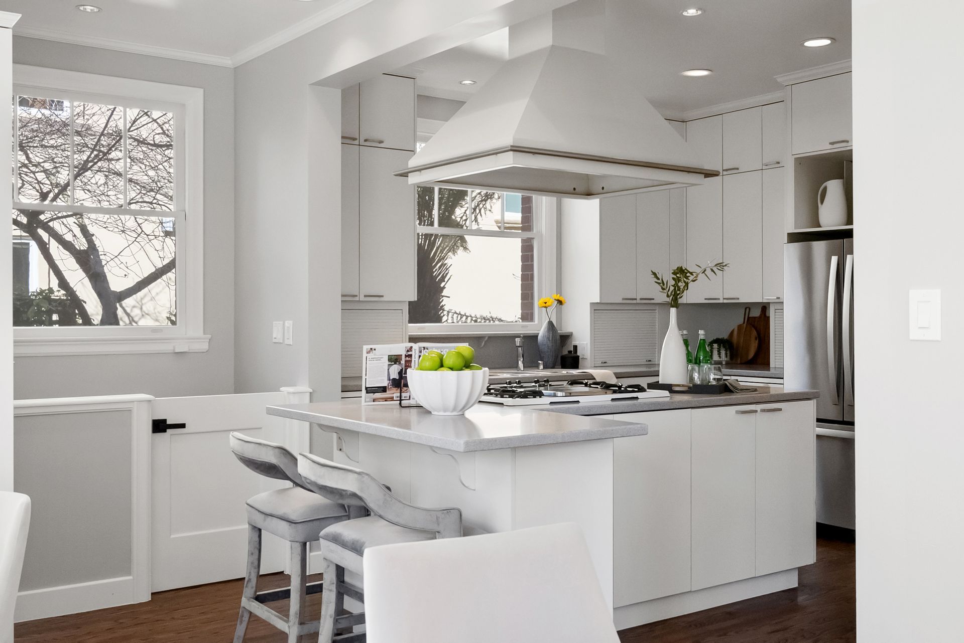 A kitchen with white cabinets , stainless steel appliances and a large island.