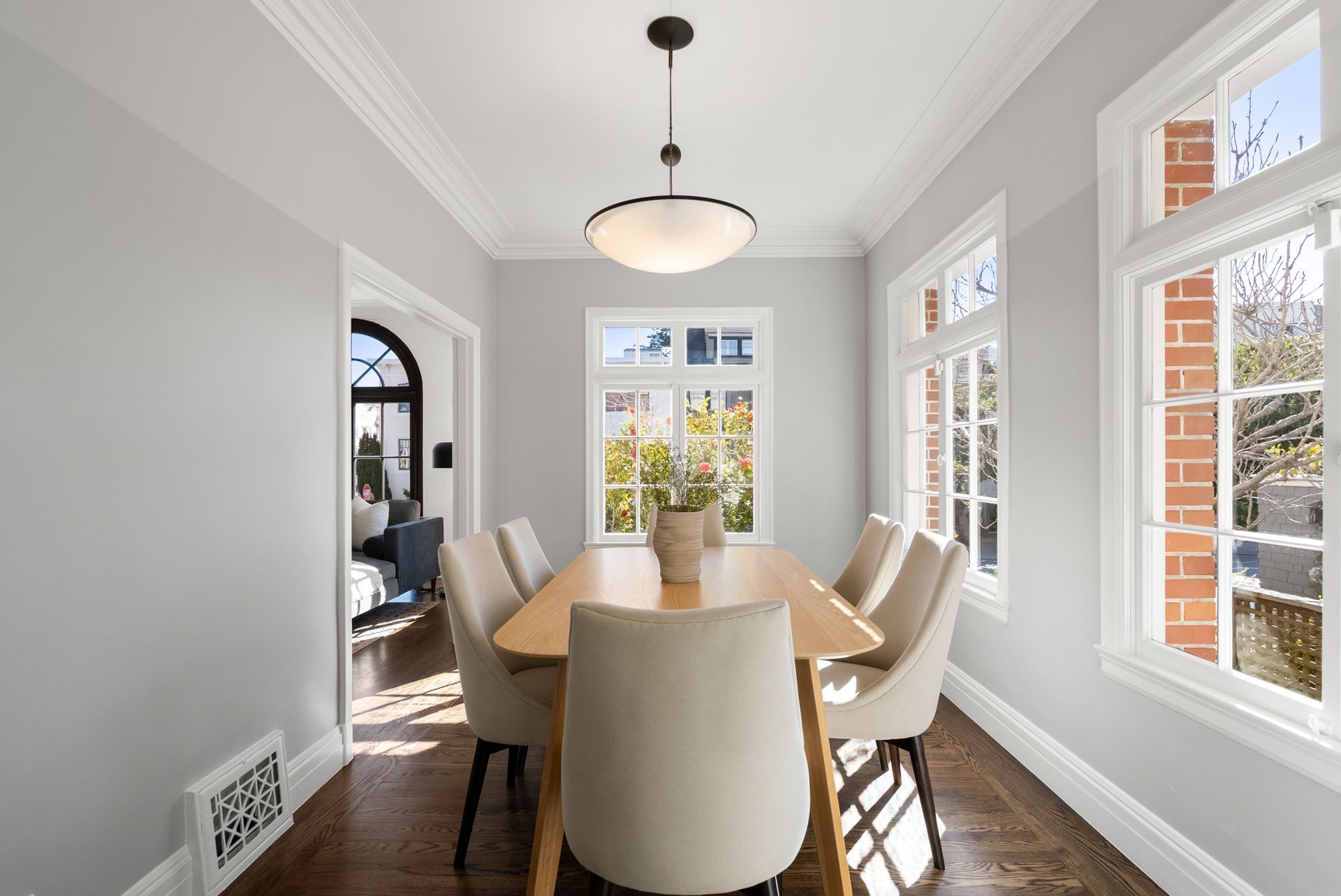 A dining room with a table and chairs and lots of windows