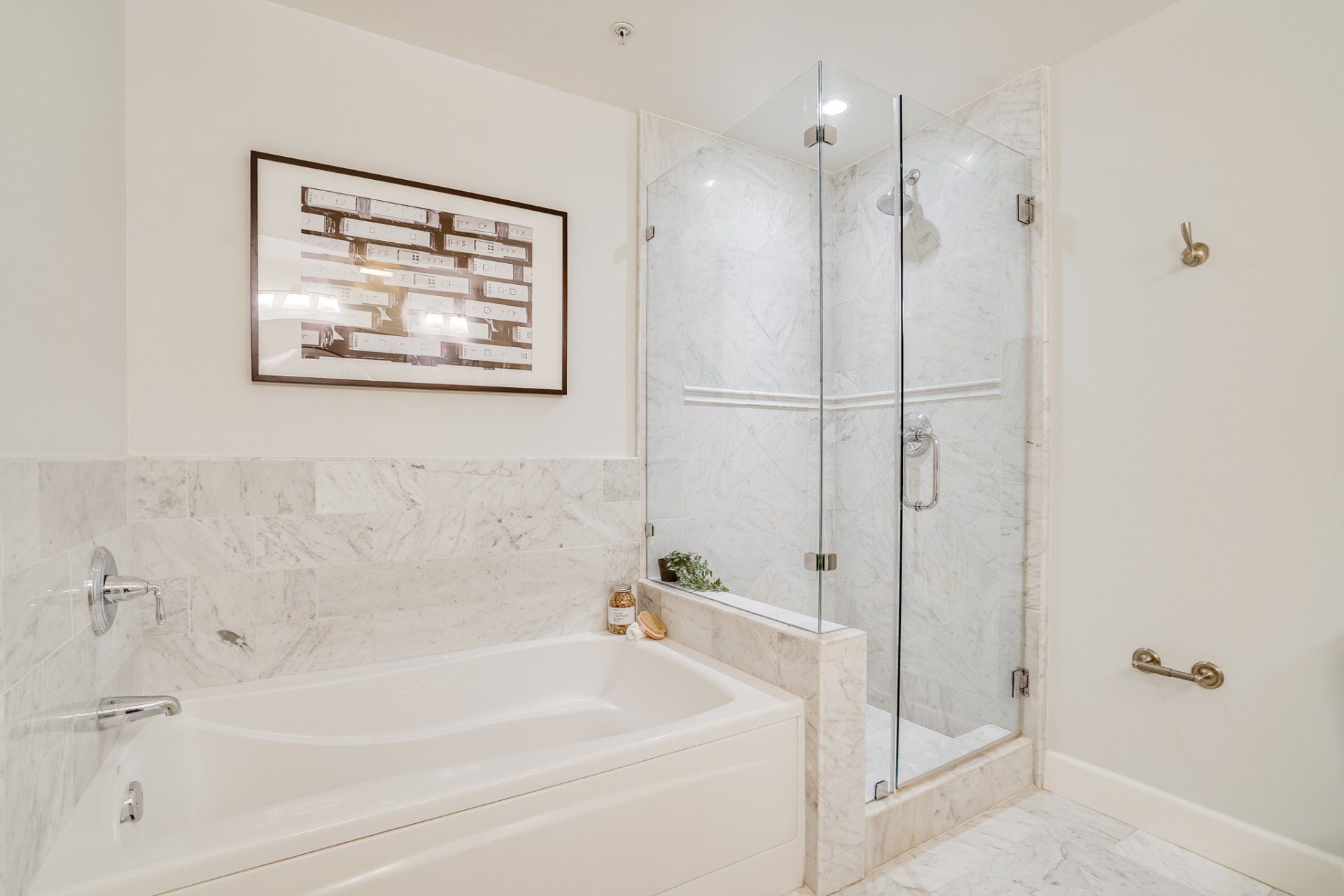 A bathroom with a tub , shower , and picture on the wall.