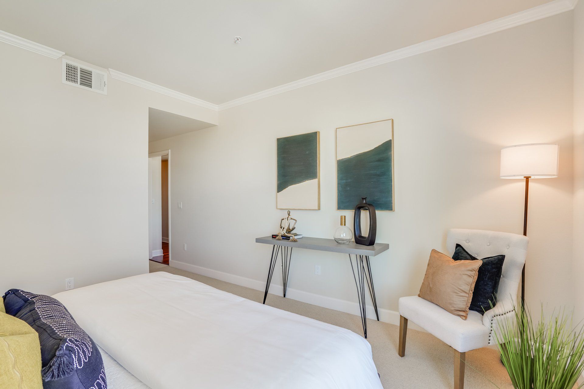 A bedroom with a bed , chair , table and lamp.