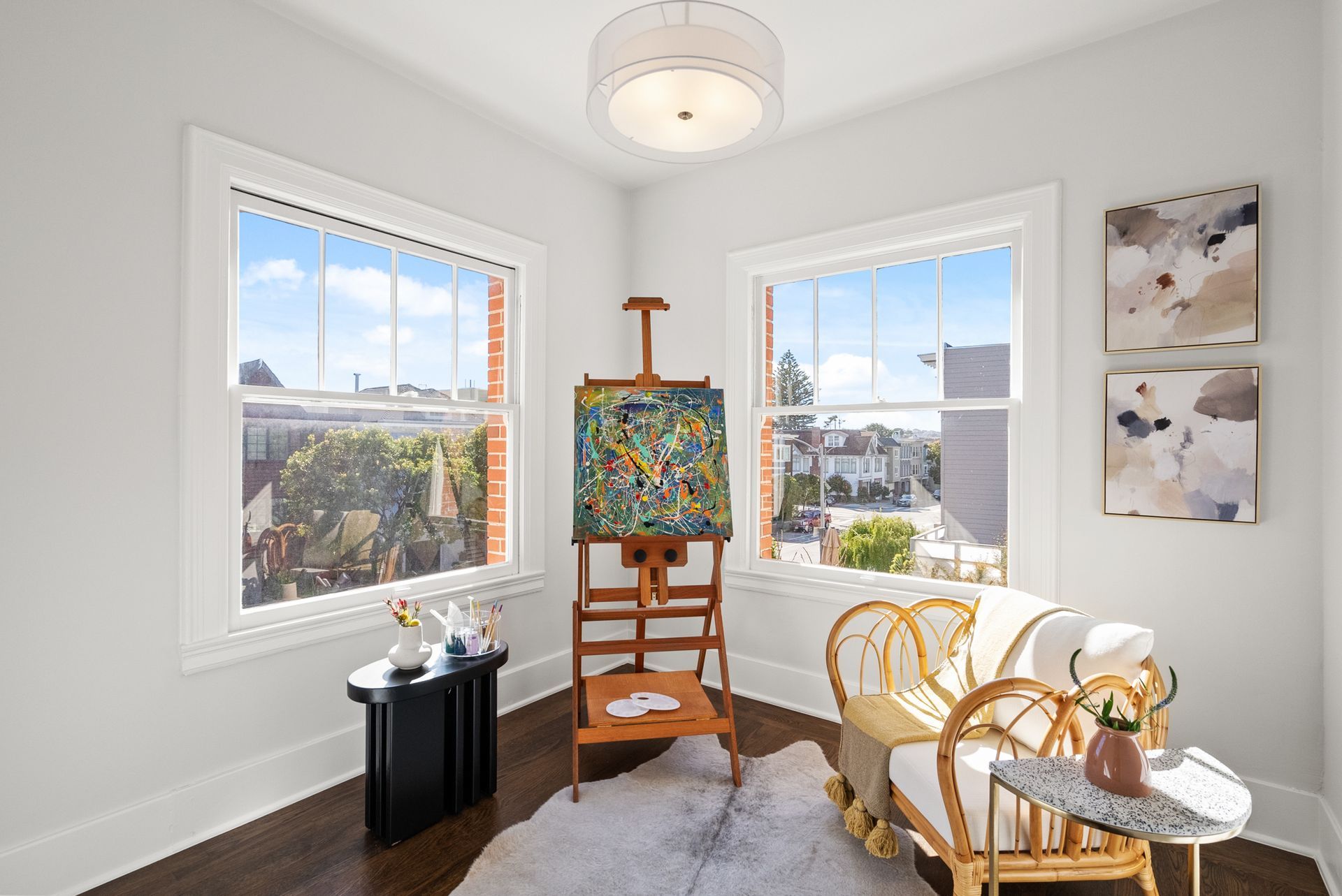 A room with a painting on an easel and a rocking chair