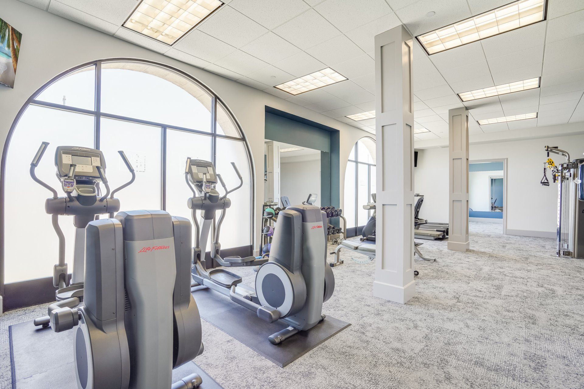 A gym with a lot of exercise equipment and a large window.
