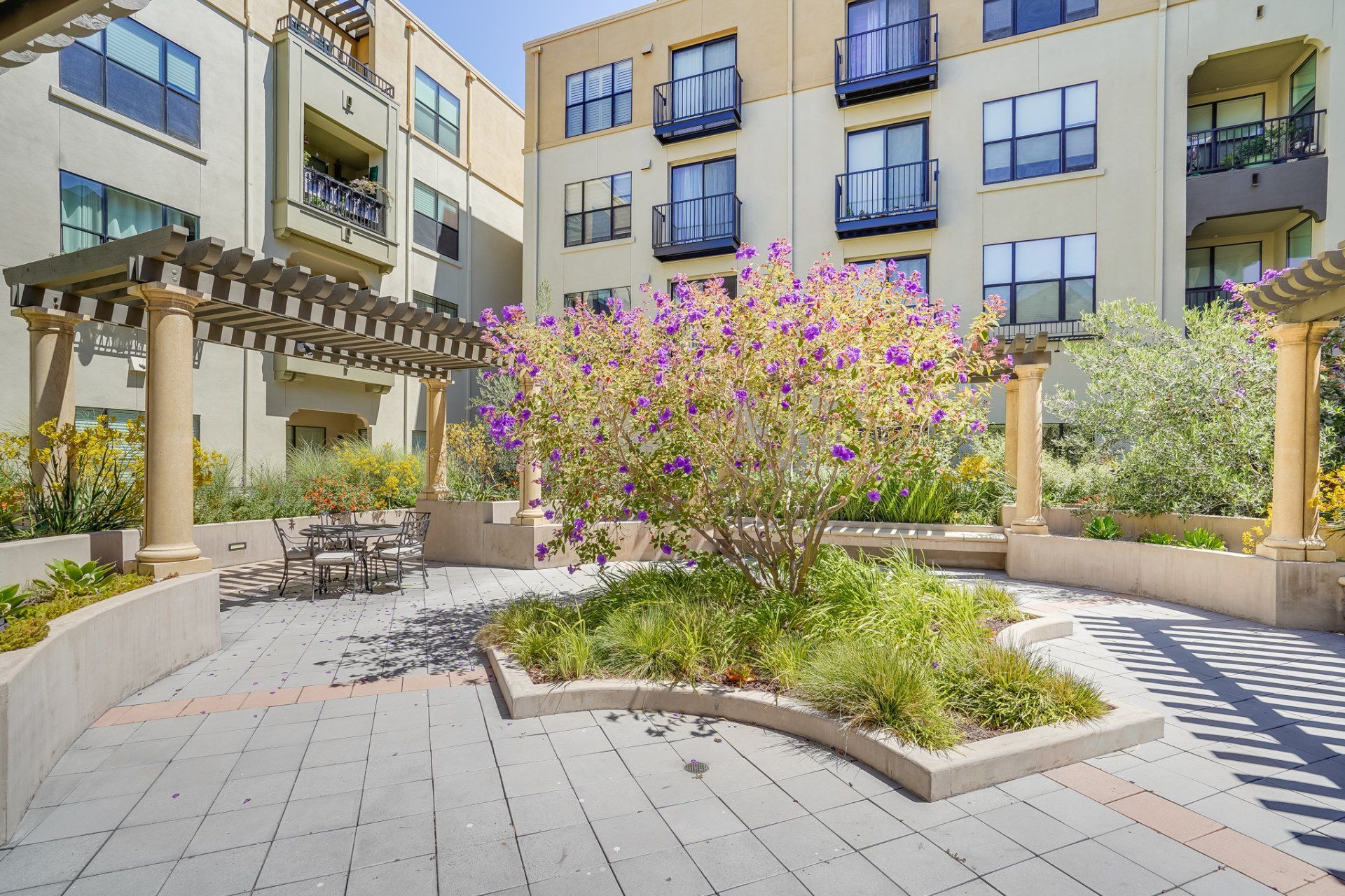 A large apartment building with a patio and flowers in front of it.