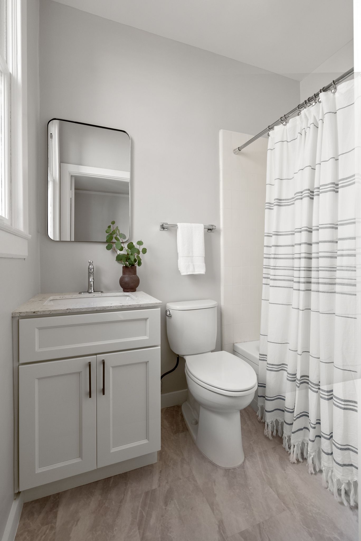 A bathroom with a toilet , sink , mirror and shower curtain.