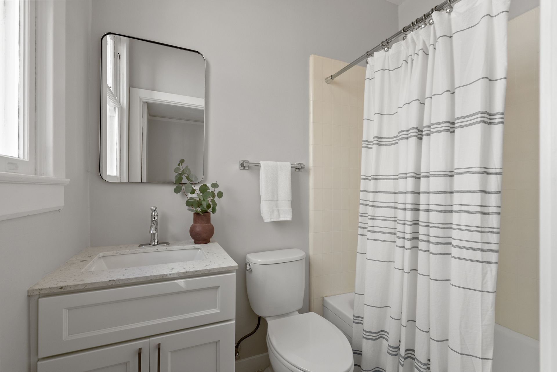A bathroom with a toilet , sink , mirror and shower curtain.
