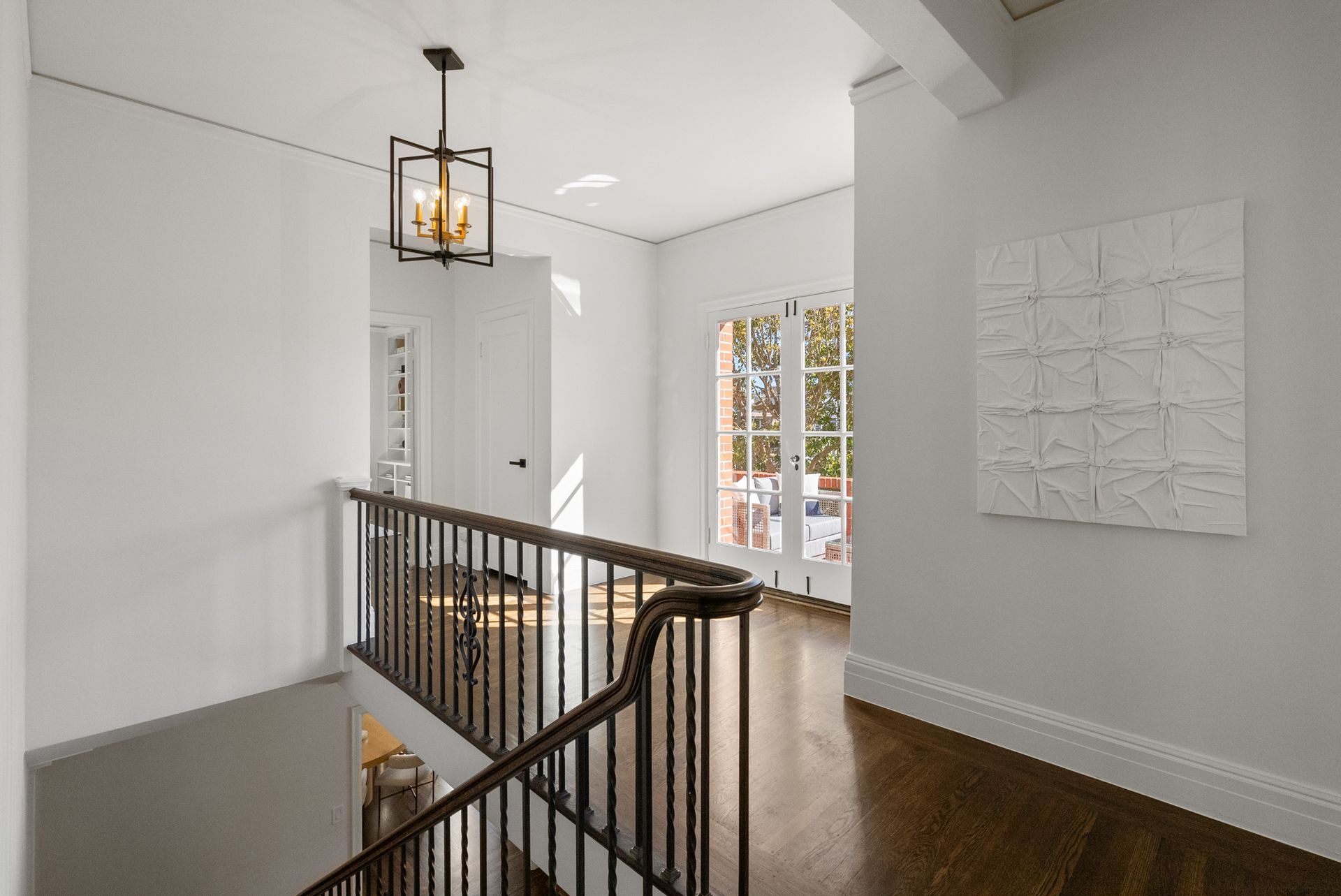 A hallway with a staircase and a painting on the wall