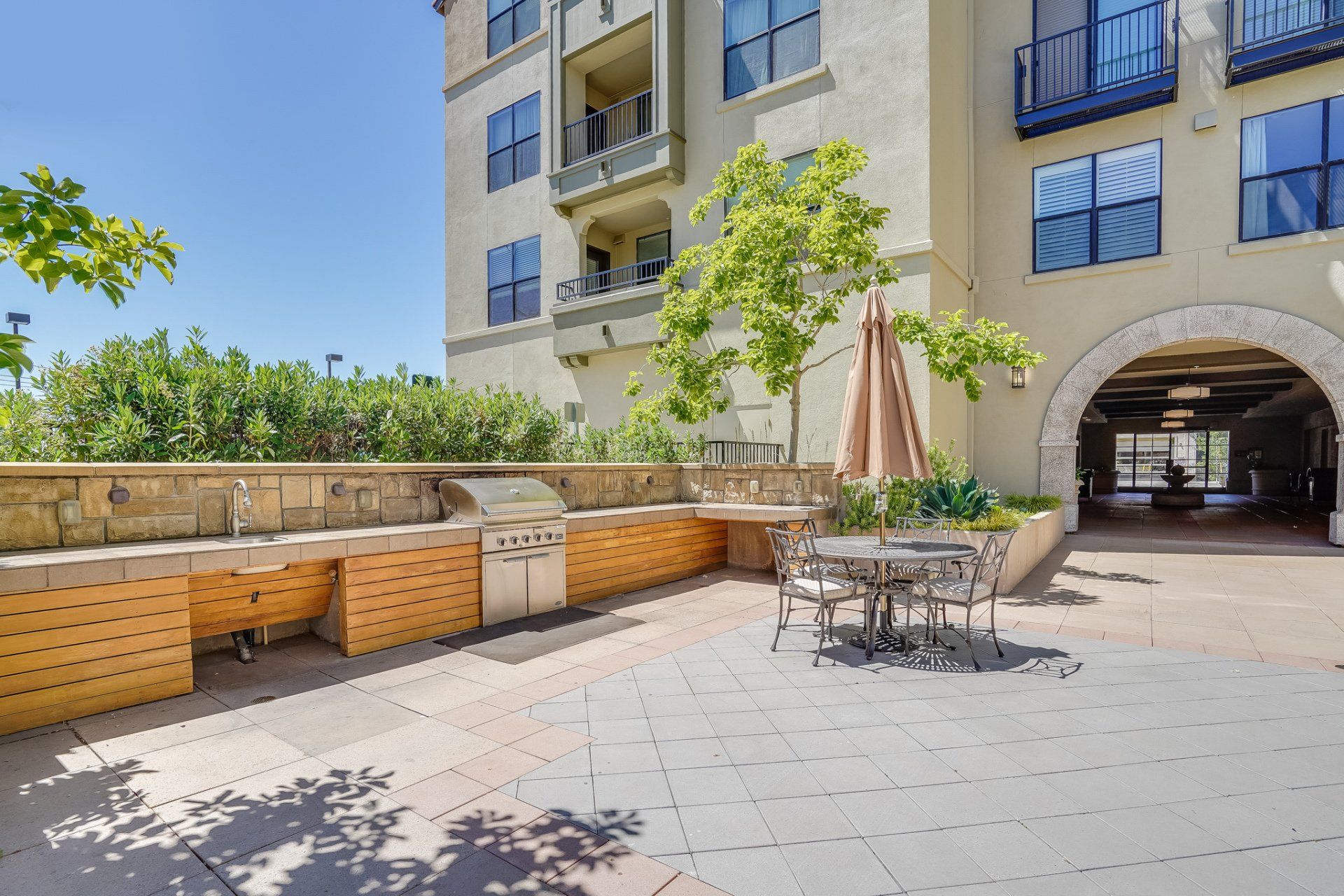 A patio with a grill and tables and chairs in front of a building.