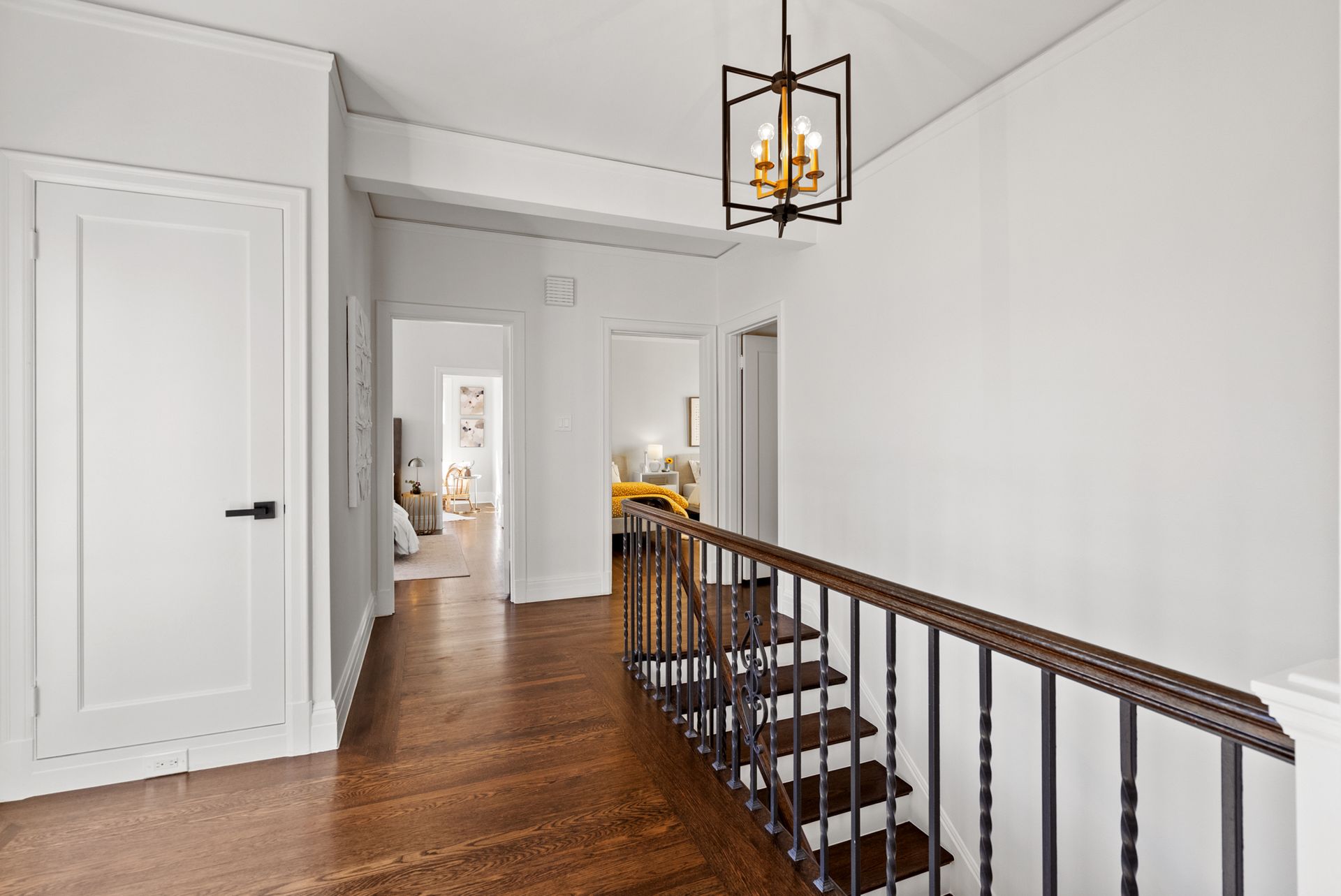 A hallway with stairs and a chandelier hanging from the ceiling.