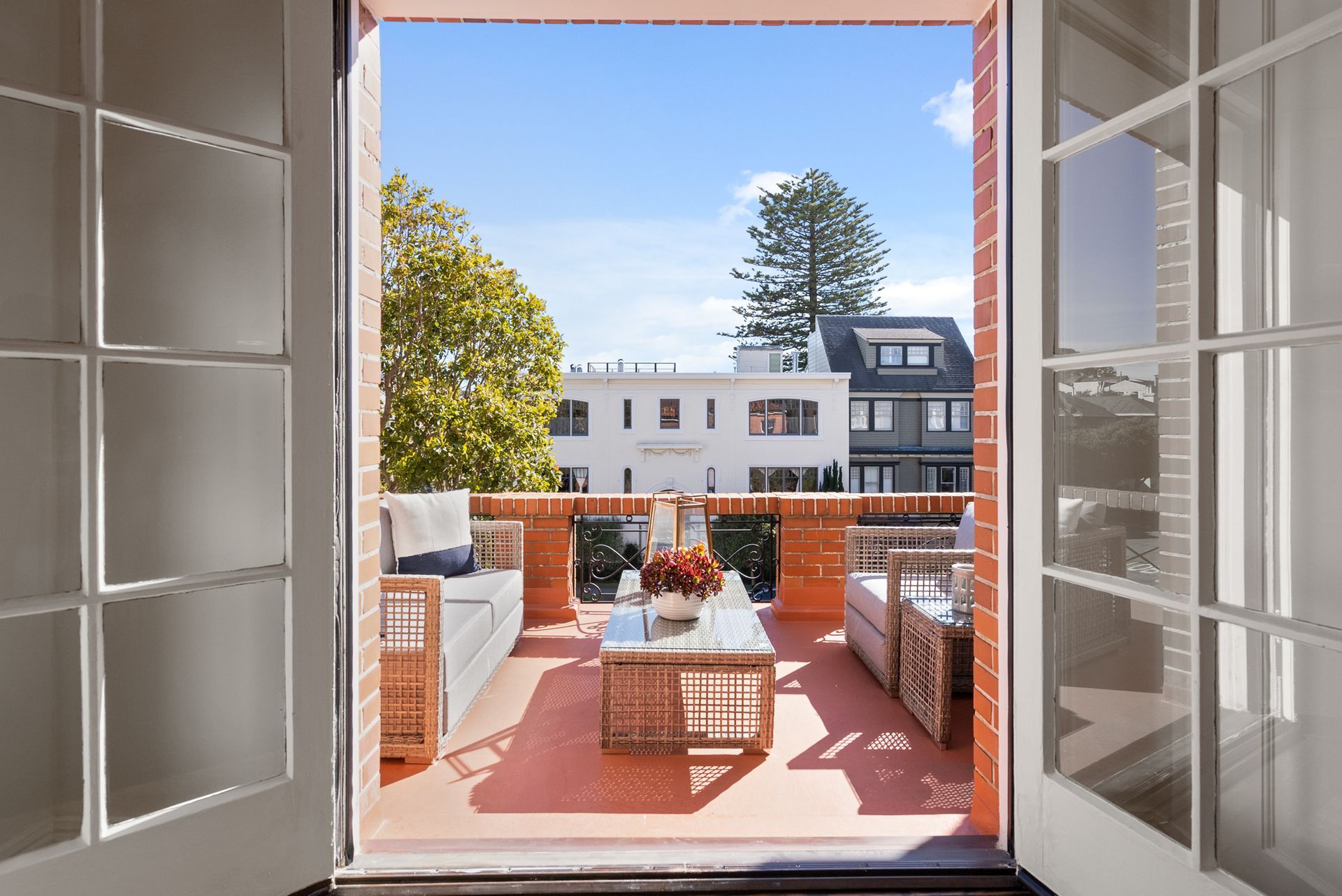 A balcony with a table and chairs is visible through an open window.