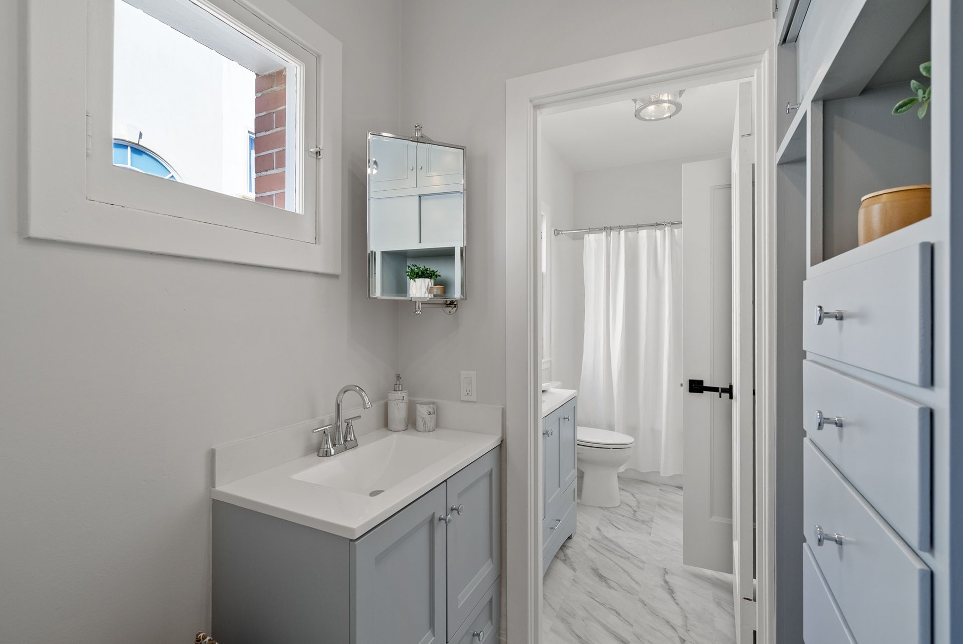 A bathroom with a sink , toilet , and window.