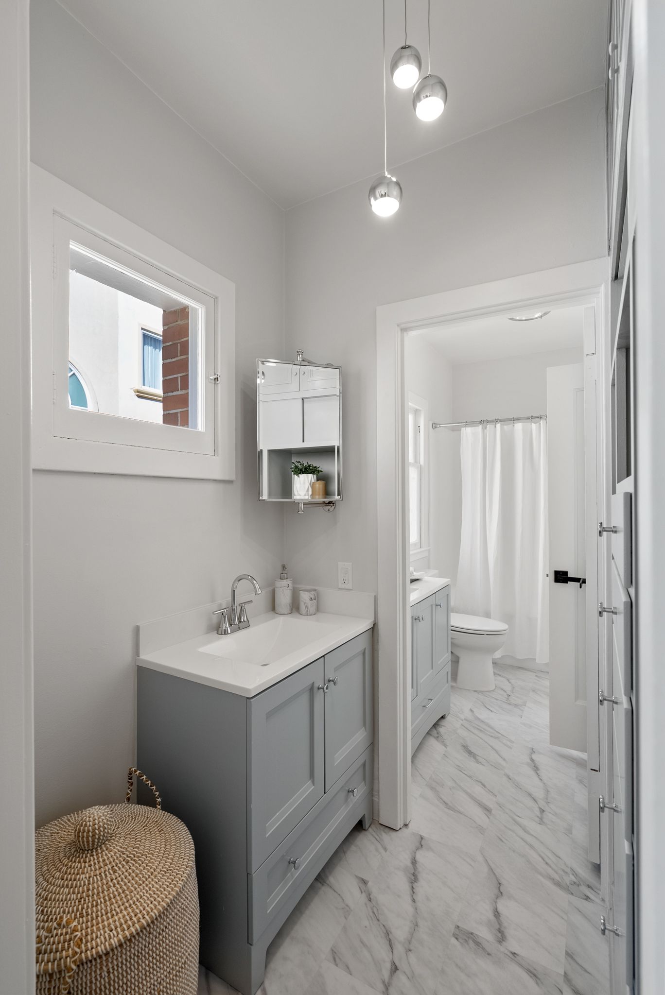 A bathroom with a sink , toilet , mirror and window.