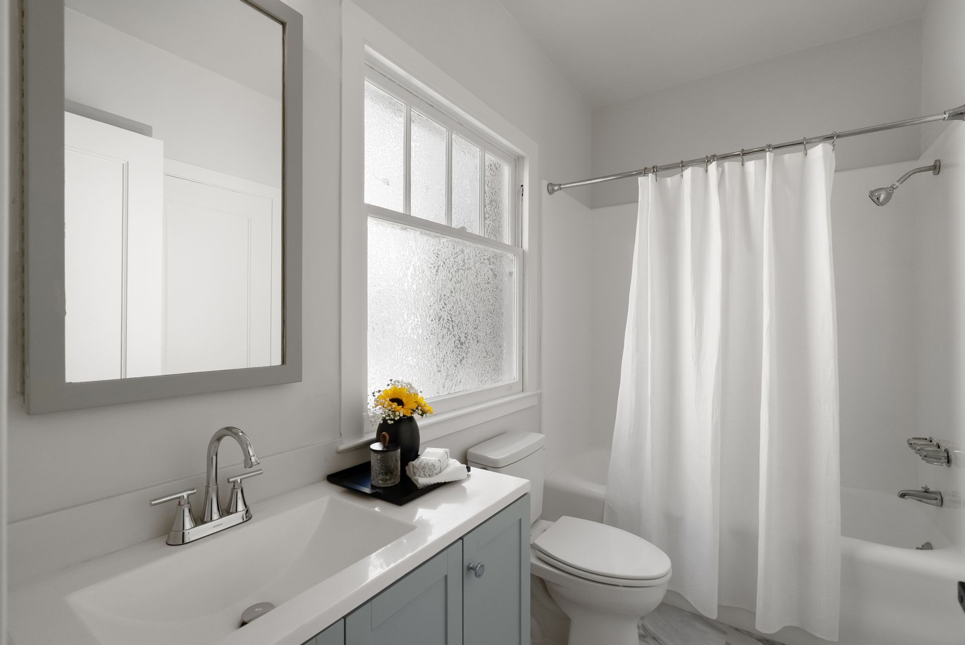 A bathroom with a toilet , sink , mirror and shower curtain.