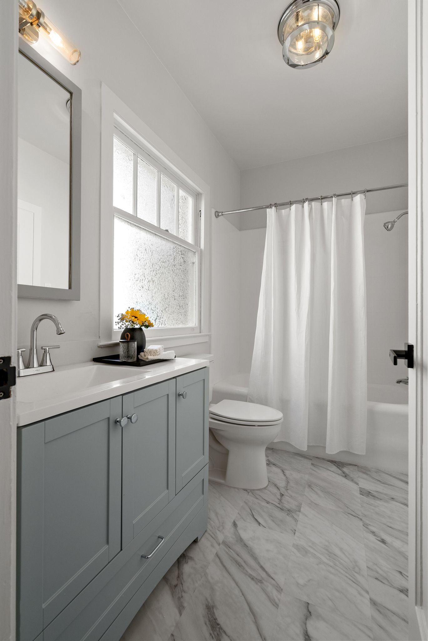 A bathroom with a toilet , sink , mirror and shower curtain.