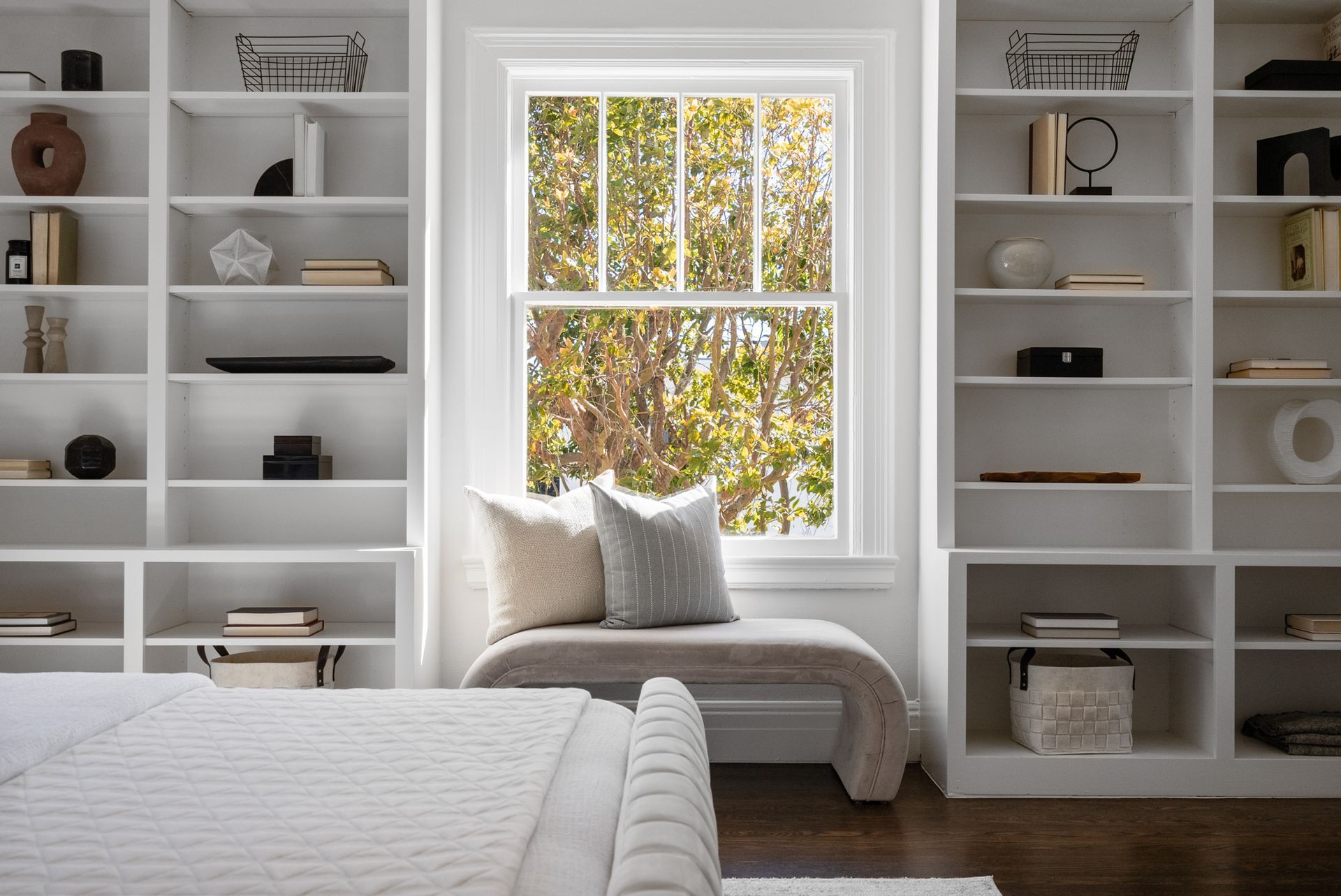 A bedroom with lots of shelves and a window seat.