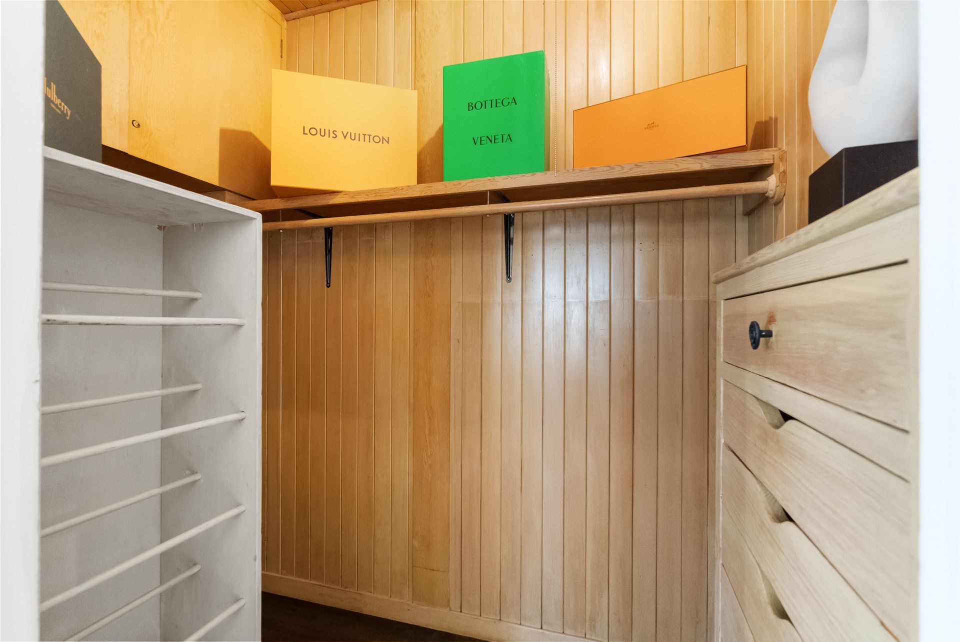 A walk in closet with wood paneling and boxes on the shelves