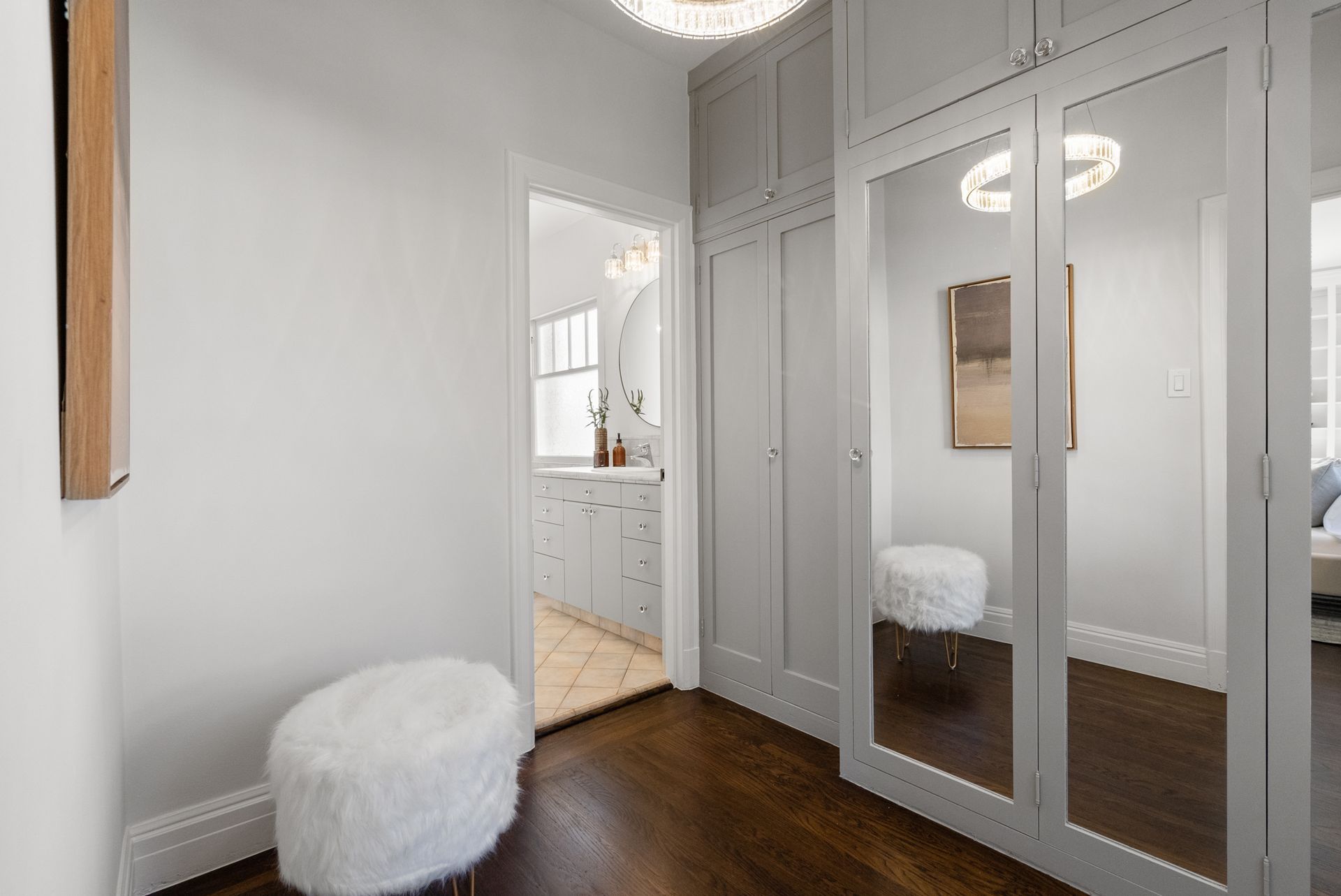 A hallway with mirrored doors and a white ottoman.