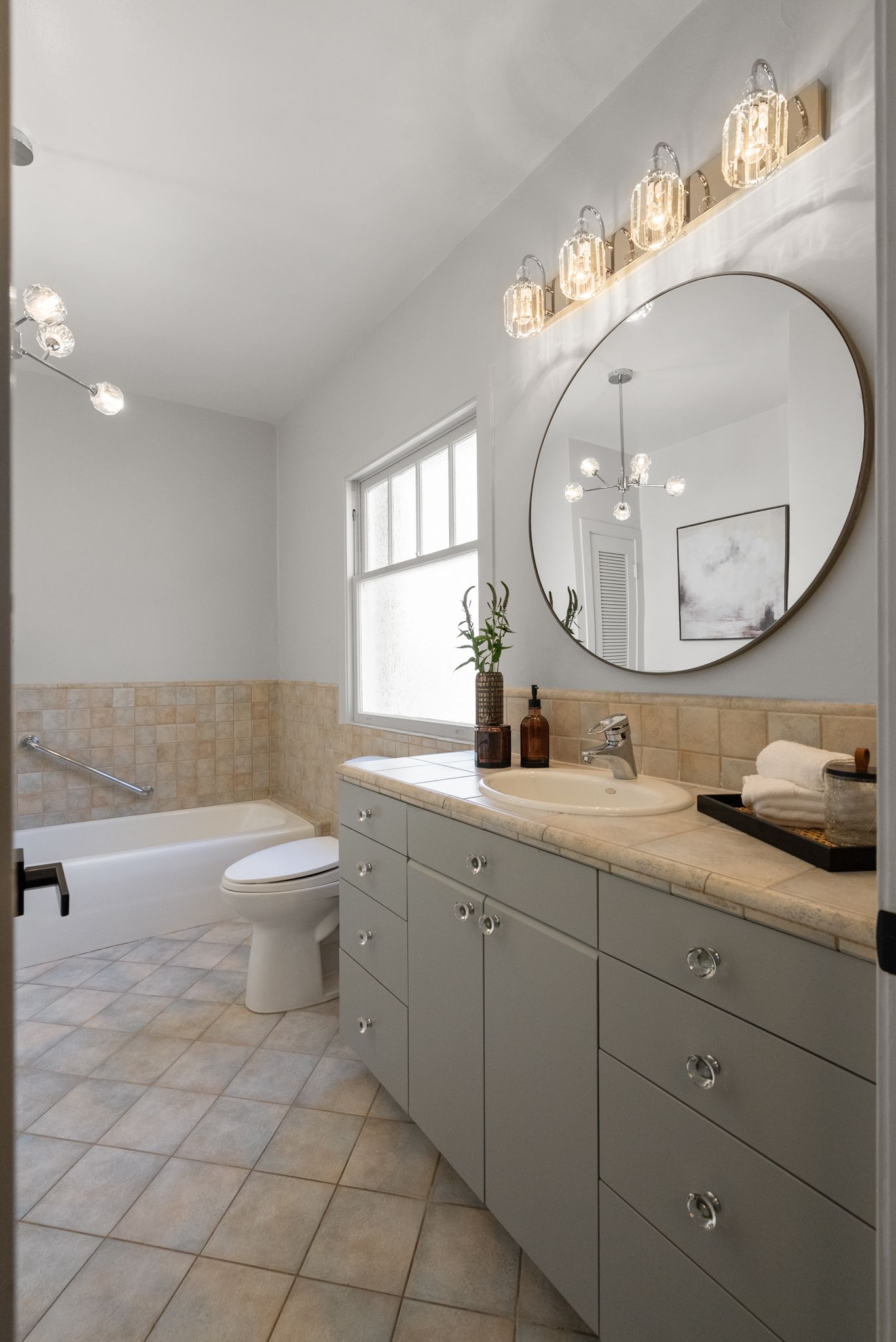 A bathroom with a sink , toilet , tub and mirror.