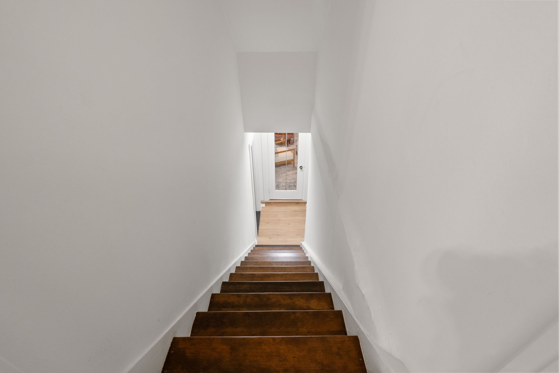 A set of wooden stairs leading up to a white wall