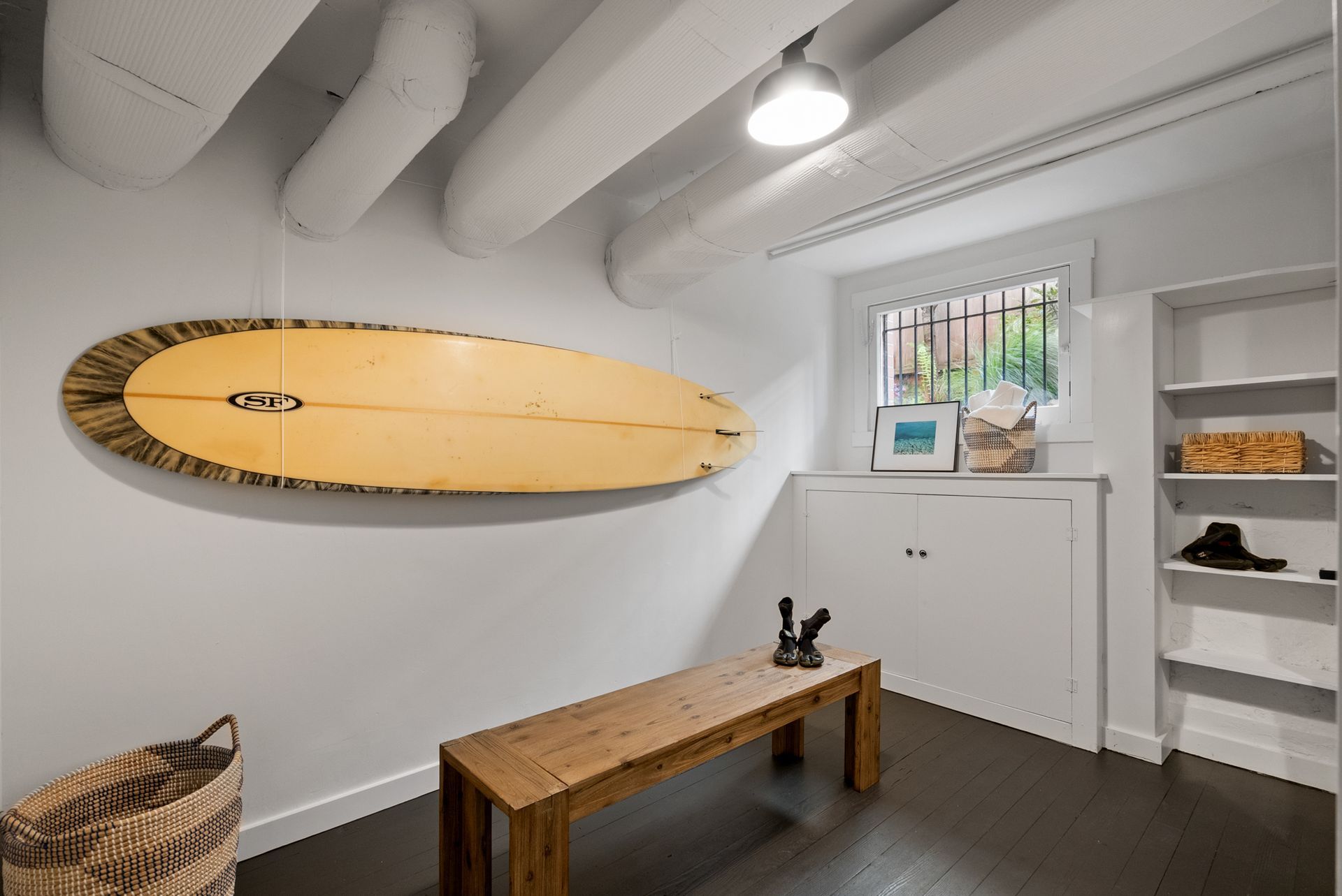 A room with a wooden bench and a surfboard on the wall