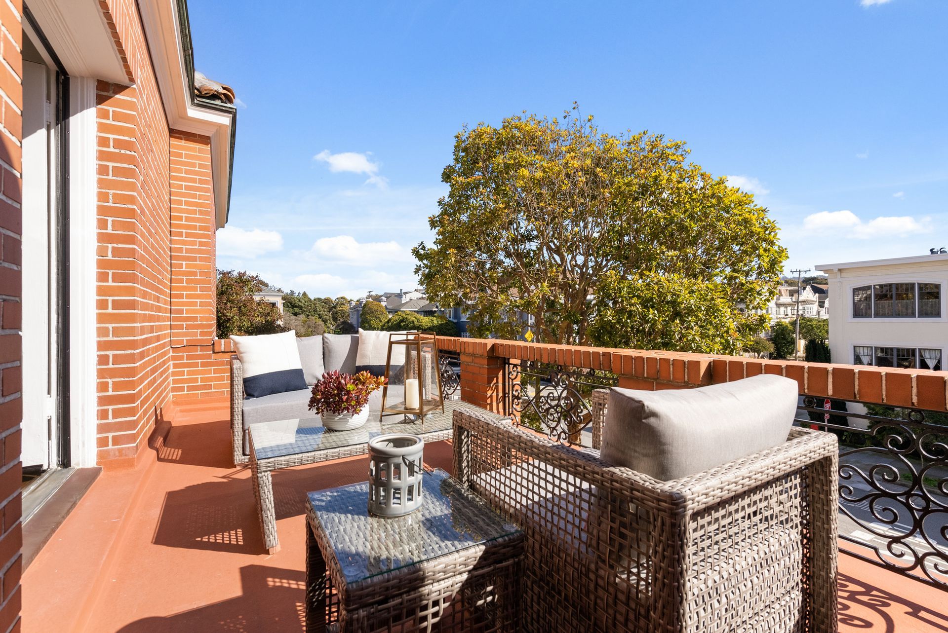 A balcony with wicker furniture and a table with a view.