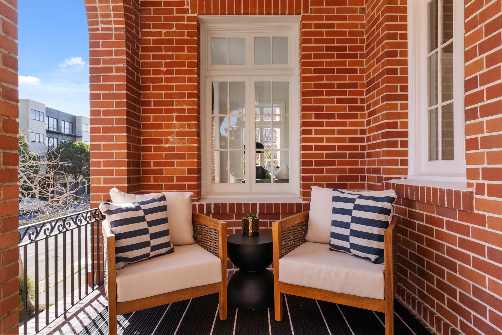 A brick balcony with two chairs and a table