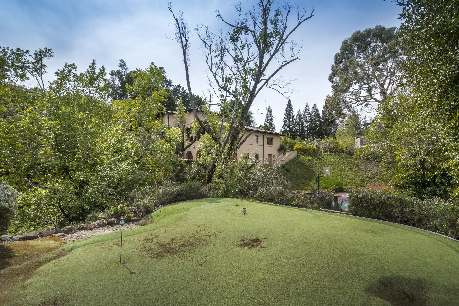 A golf course with trees and a house in the background