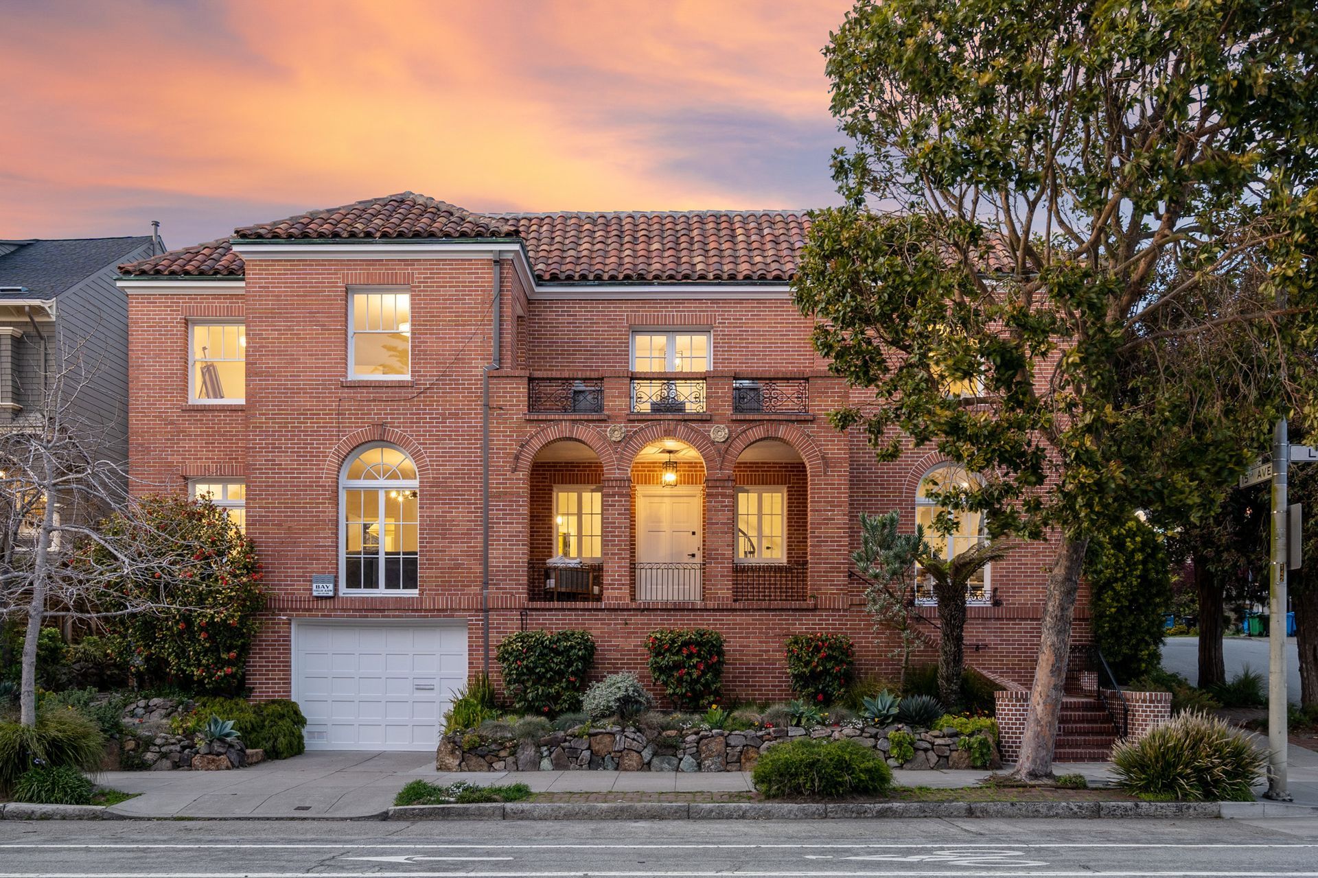 A large brick house with a lot of windows and a sunset in the background.