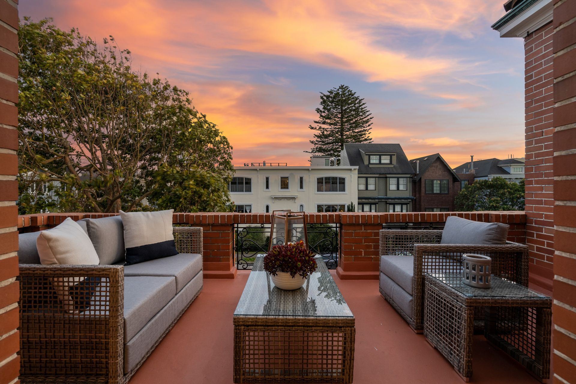 A balcony with a couch and chairs and a table at sunset