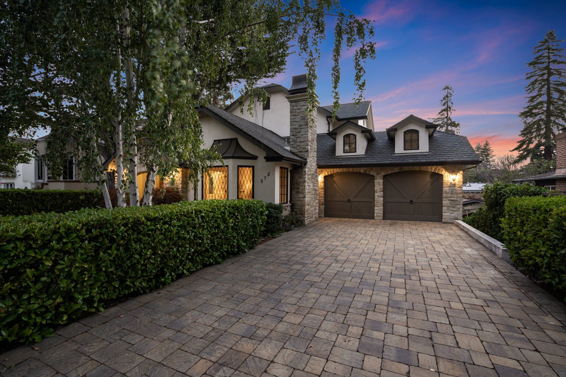 A large house with two garages and a brick driveway.