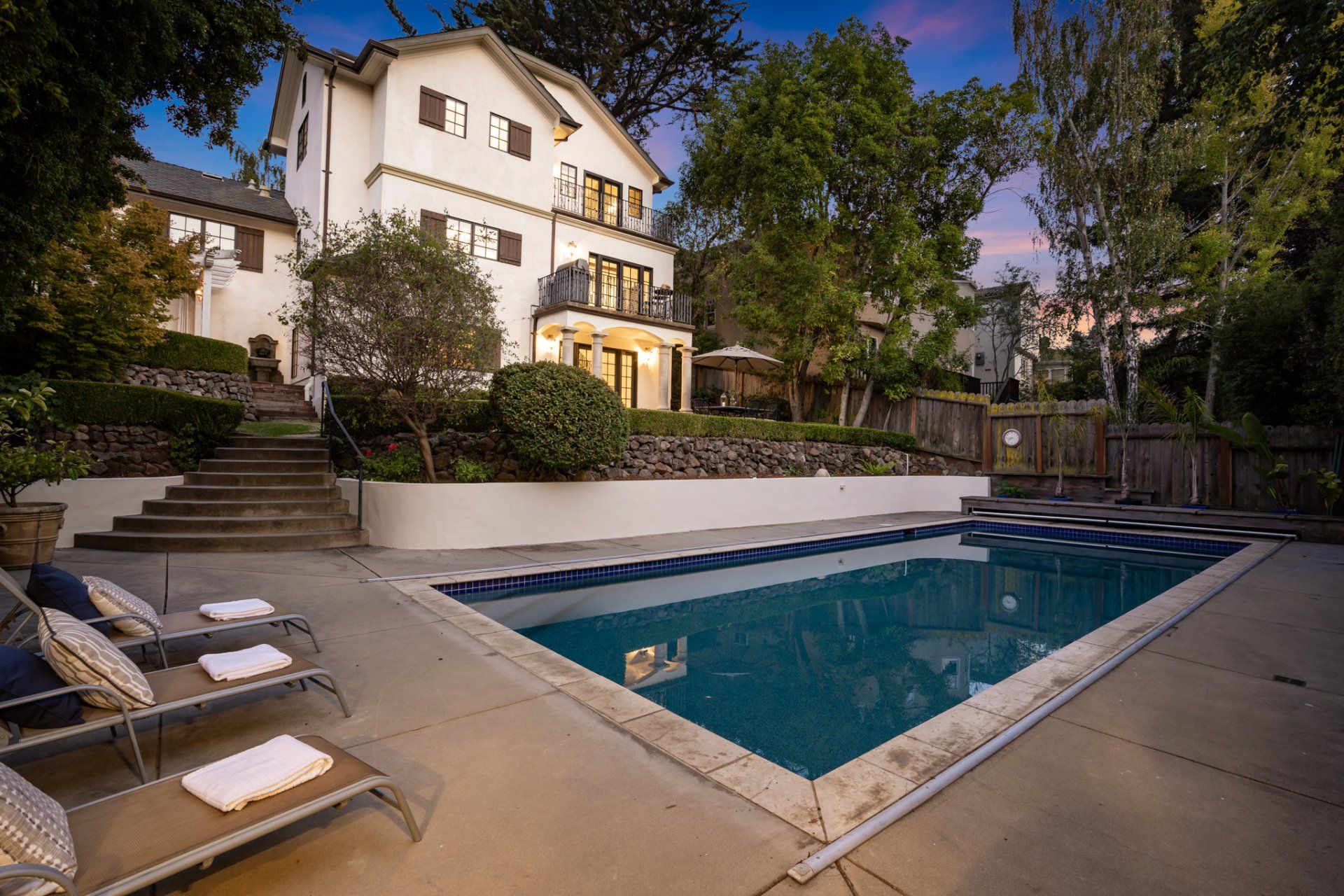 A house with a pool, steps lead up to the house from the pool deck.