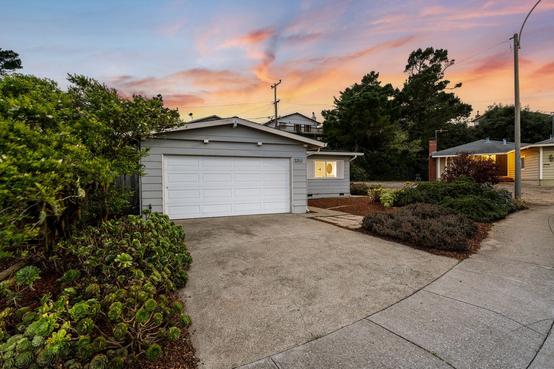 A house with a garage and a driveway at sunset.