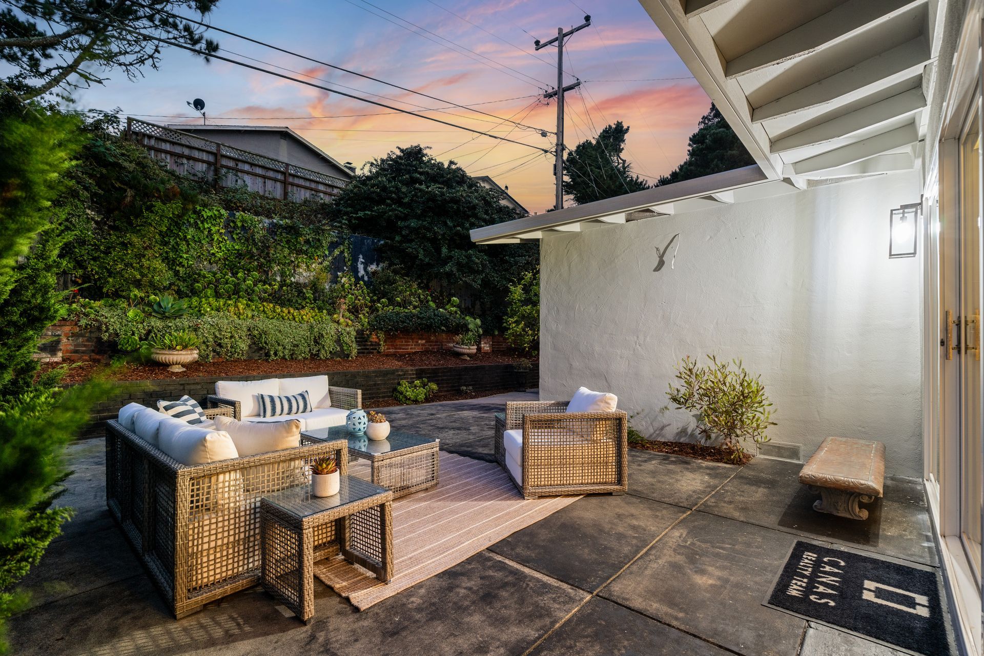 Patio with furniture, a concrete floor, and a bench, bathed in soft evening light.