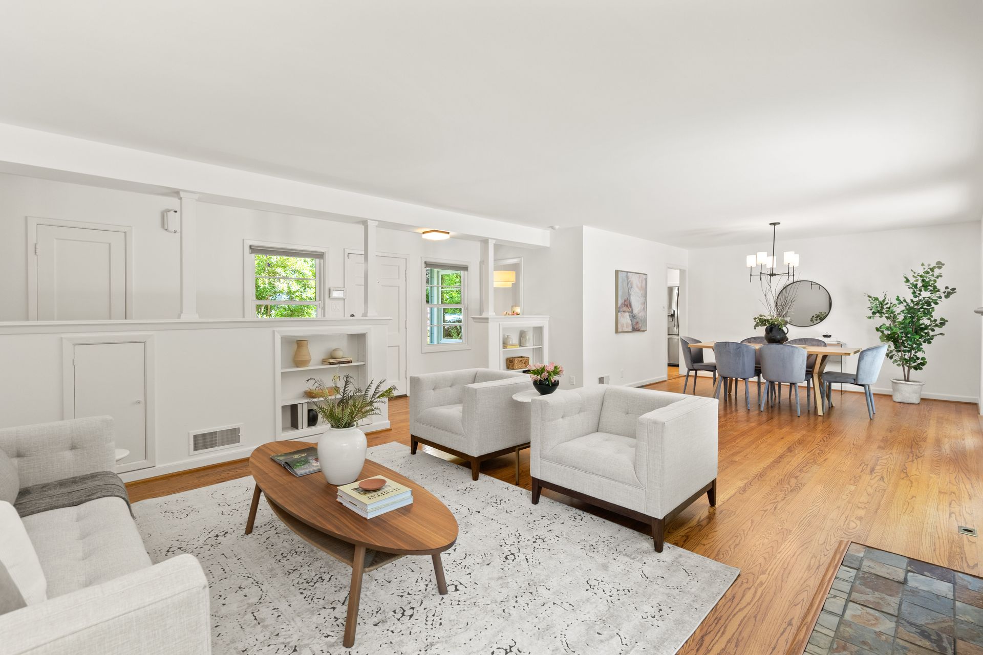 A living room with a couch , two chairs , a coffee table and a dining table.
