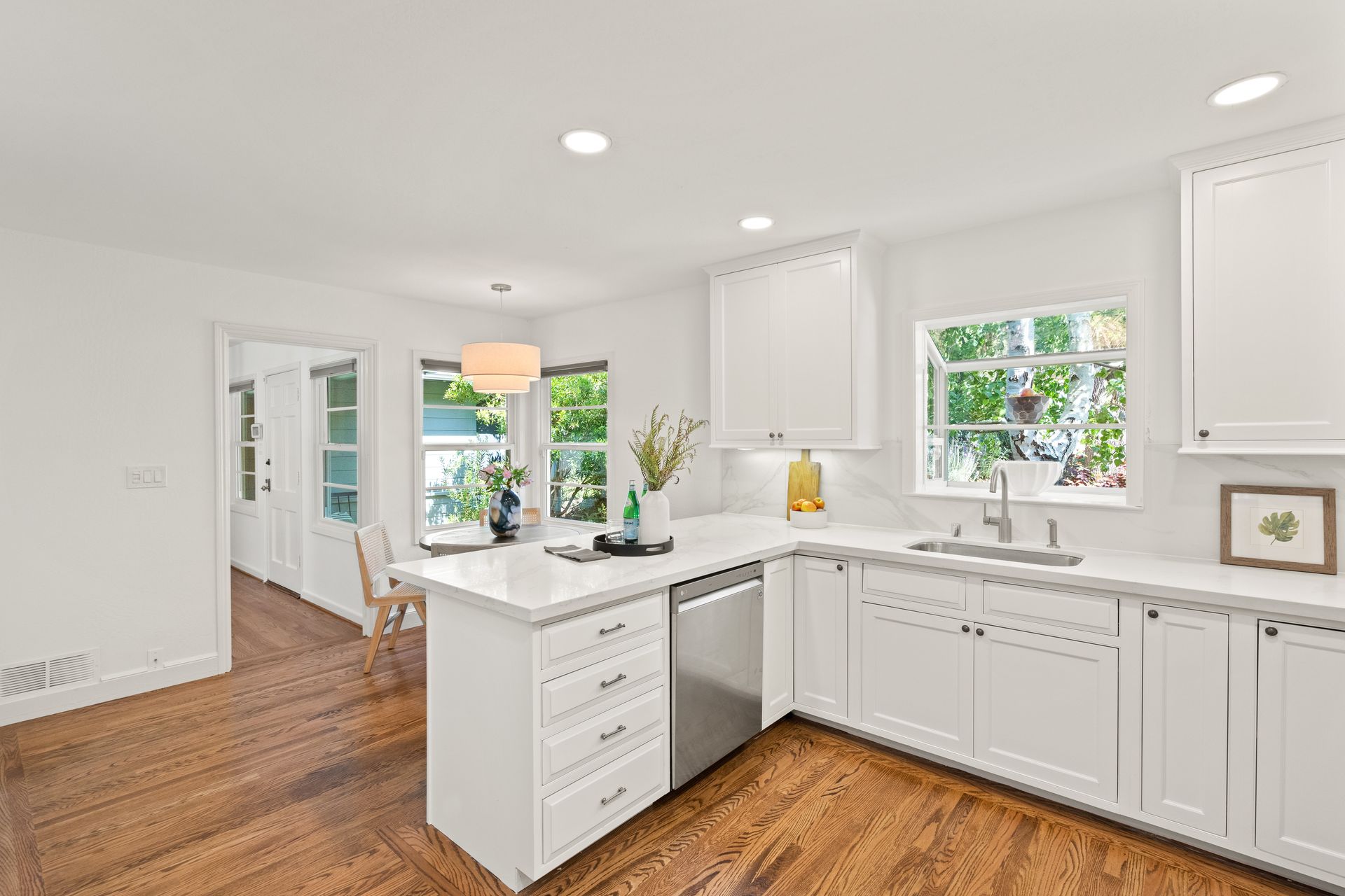 A kitchen with white cabinets , stainless steel appliances , and hardwood floors.