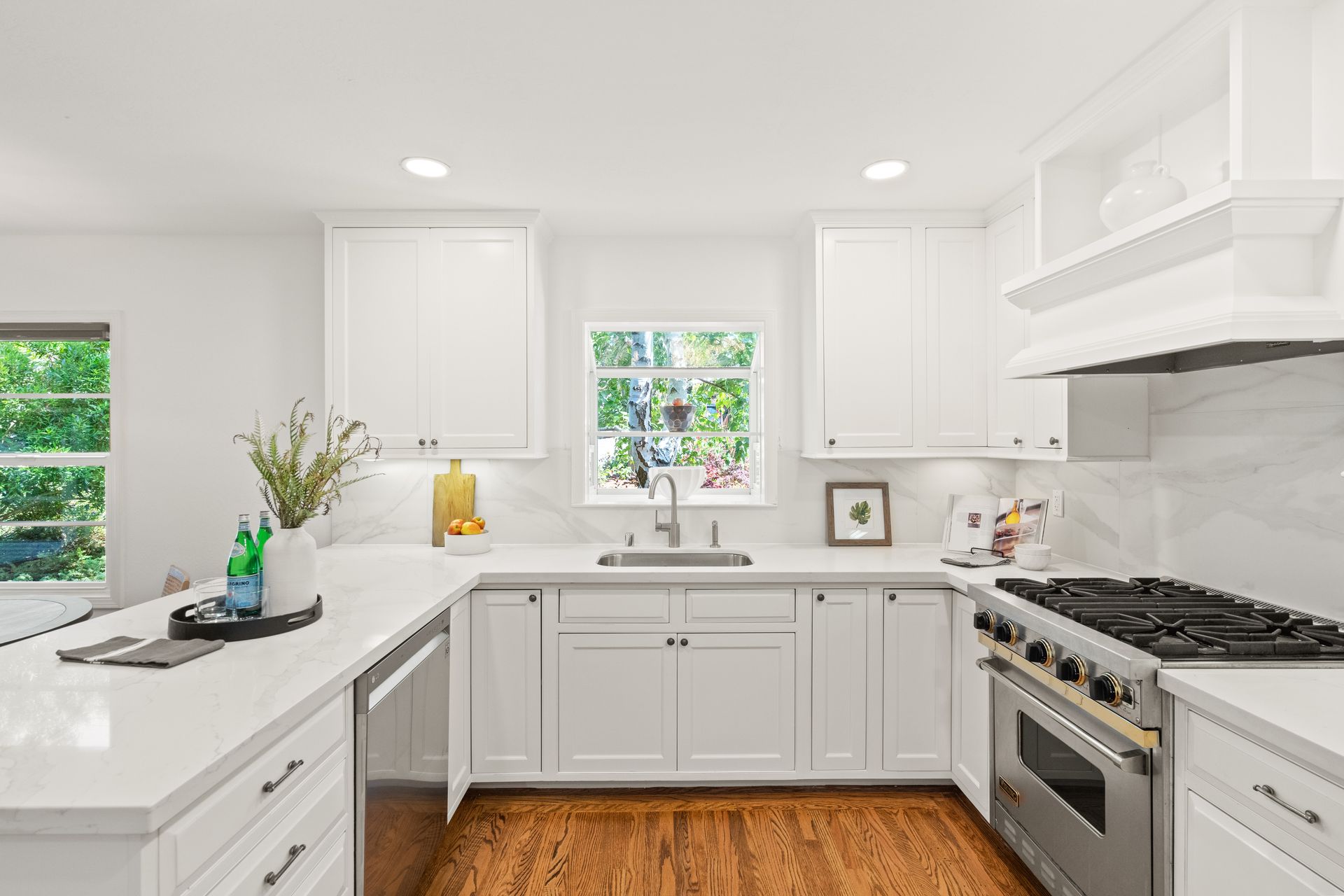 A kitchen with white cabinets , stainless steel appliances , and hardwood floors.